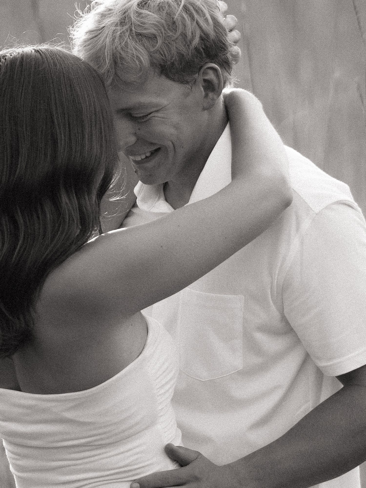 Black and white romantic couple portrait with woman embracing smiling man outdoors at an engagement shoot in Minnesota.