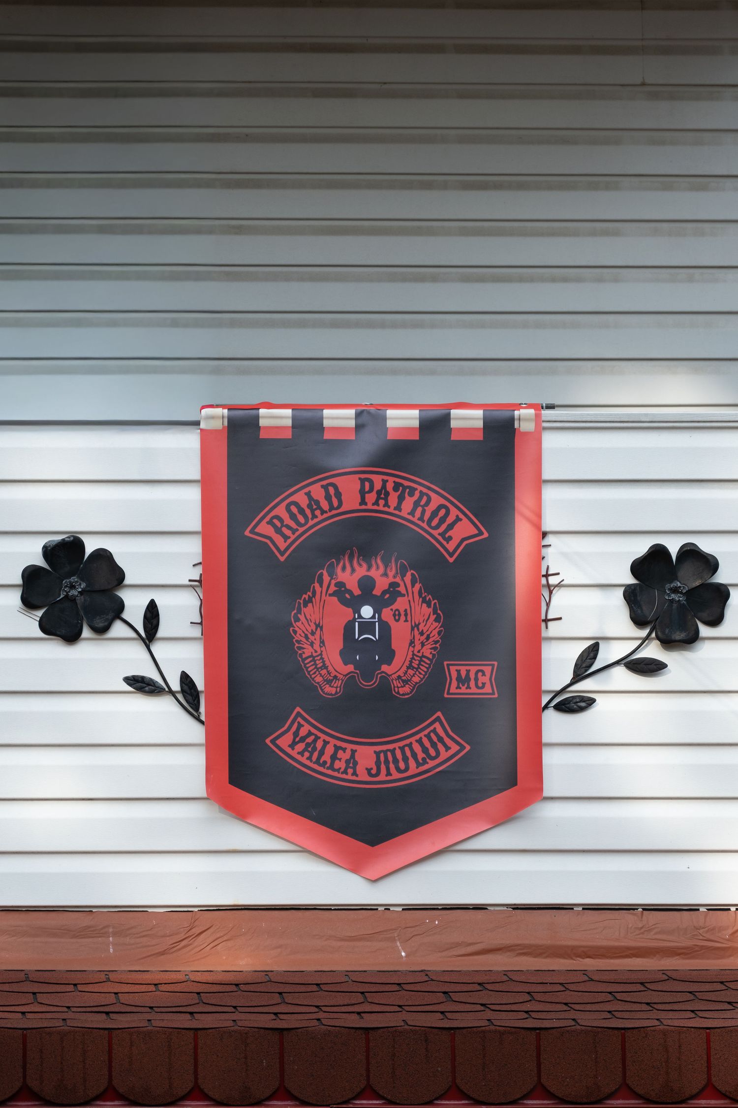 Road Patrol MC Valea Jiului motorcycle club banner hanging on a wall with decorative black metal flowers.