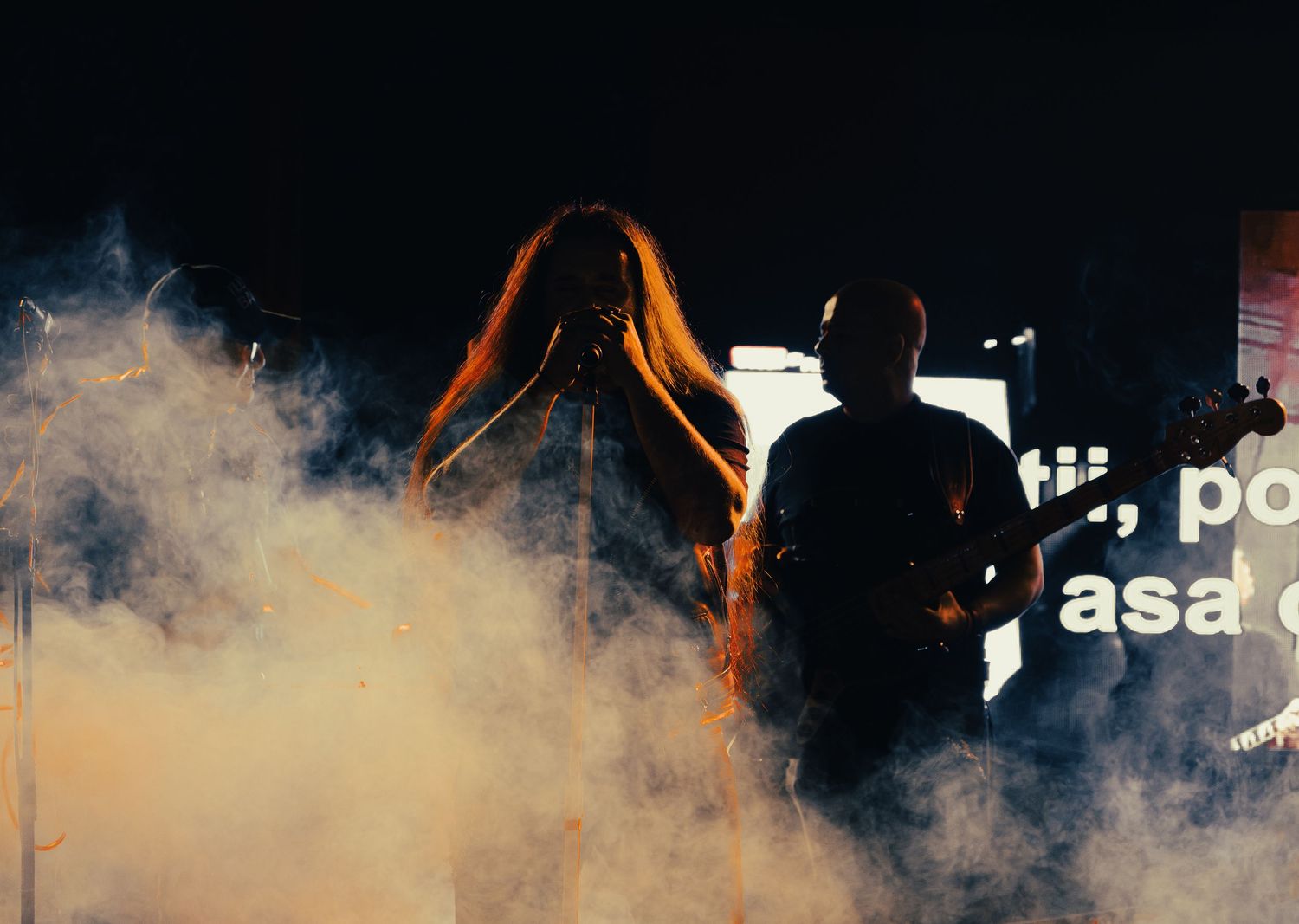 Two silhouetted musicians performing on a smoky stage with dramatic backlighting.