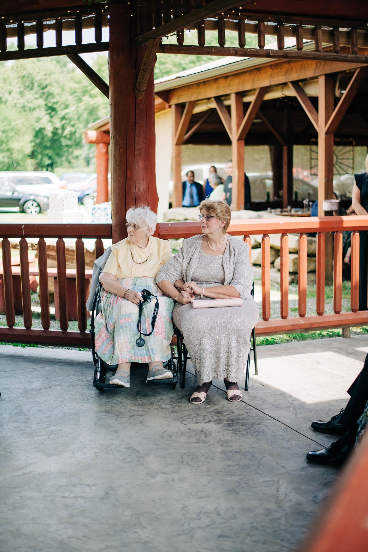 groom's mother and grandmother holding hands in their seats