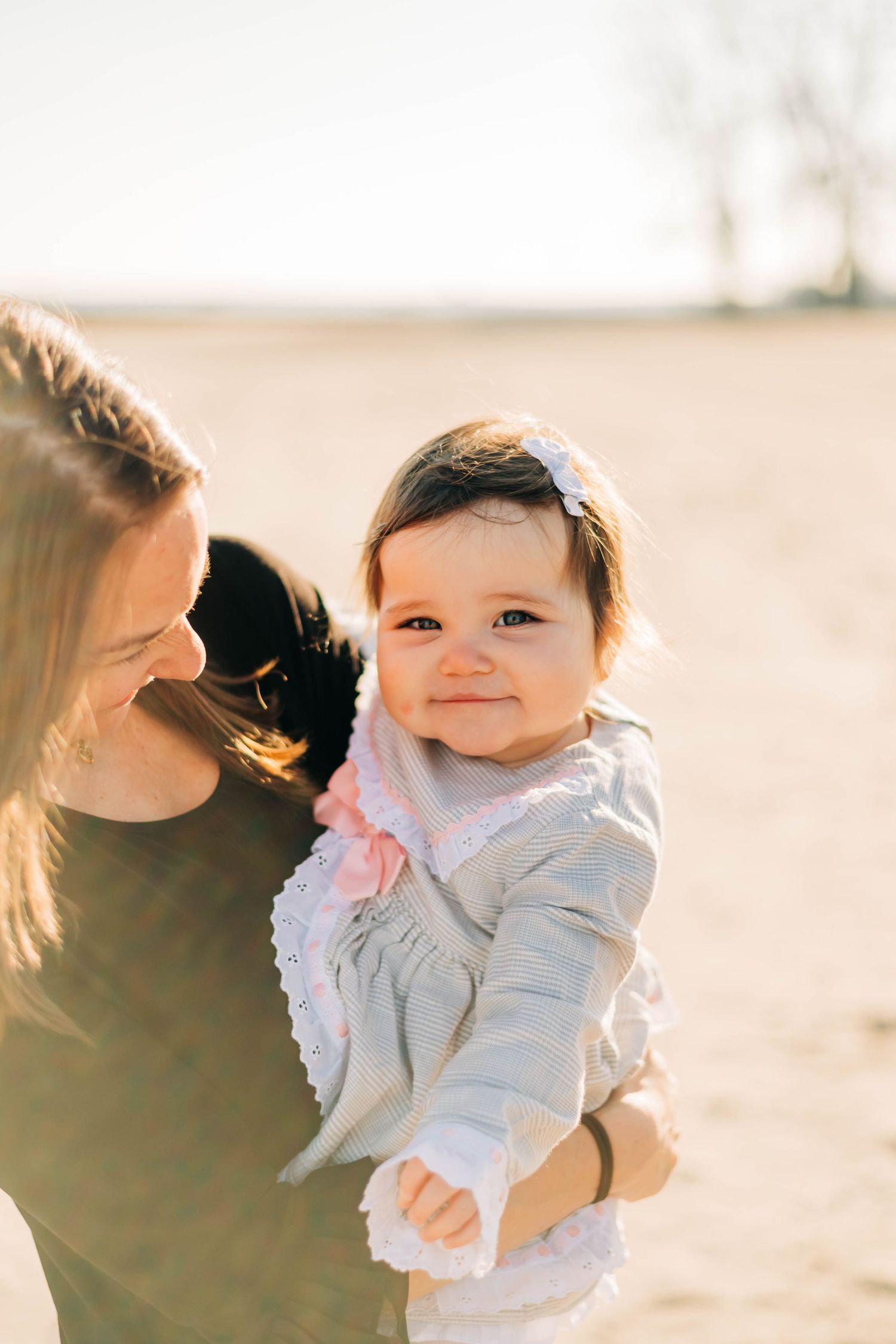 Photo of baby girl smiling at camera being held by her mother