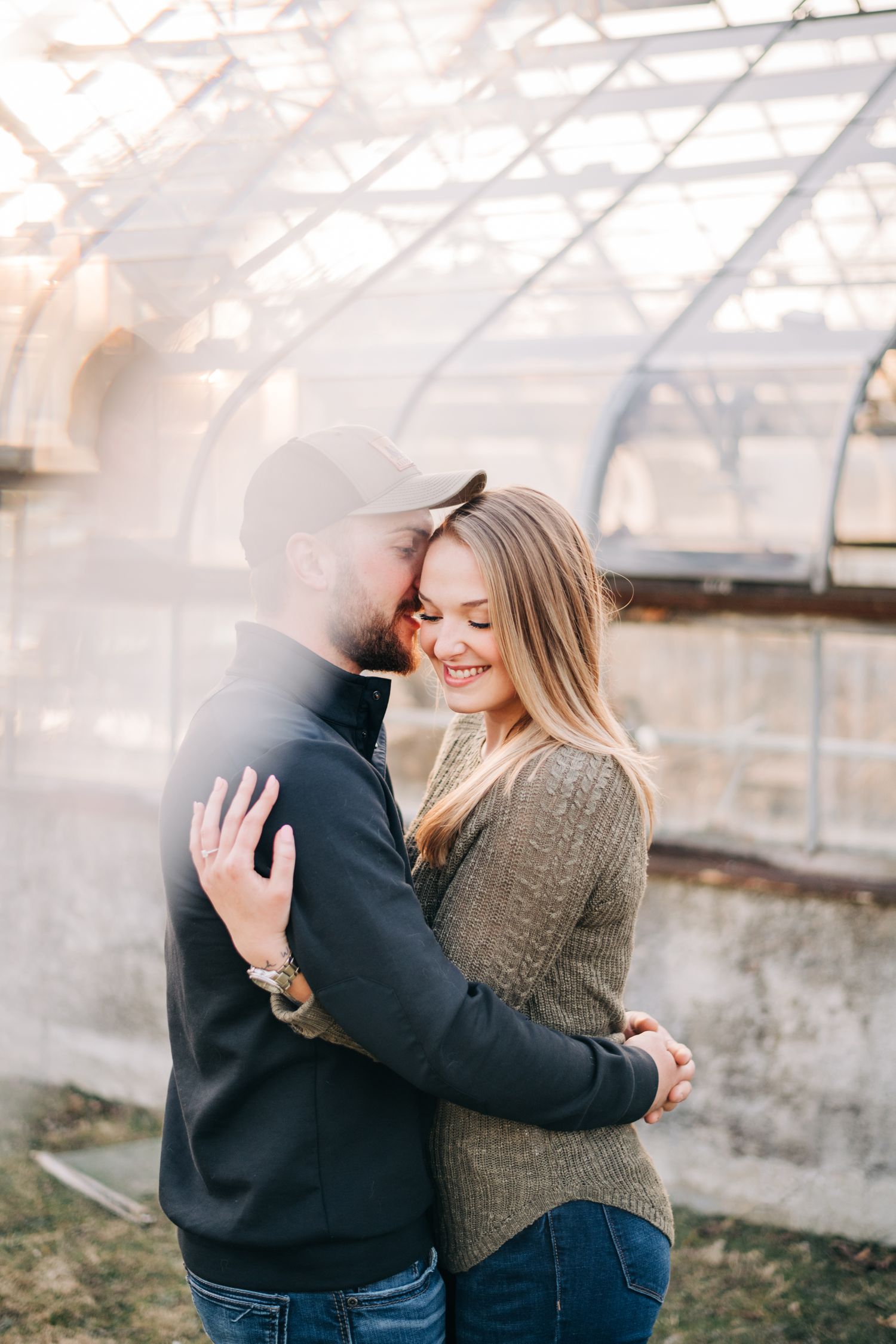 photo of engaged couple hugging in front of an abandoned greenhouse, fractal prism in corner creating a mirror effect
