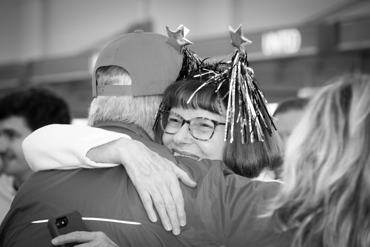 Woman with festive star headband sharing a warm embrace with a man in a baseball cap.