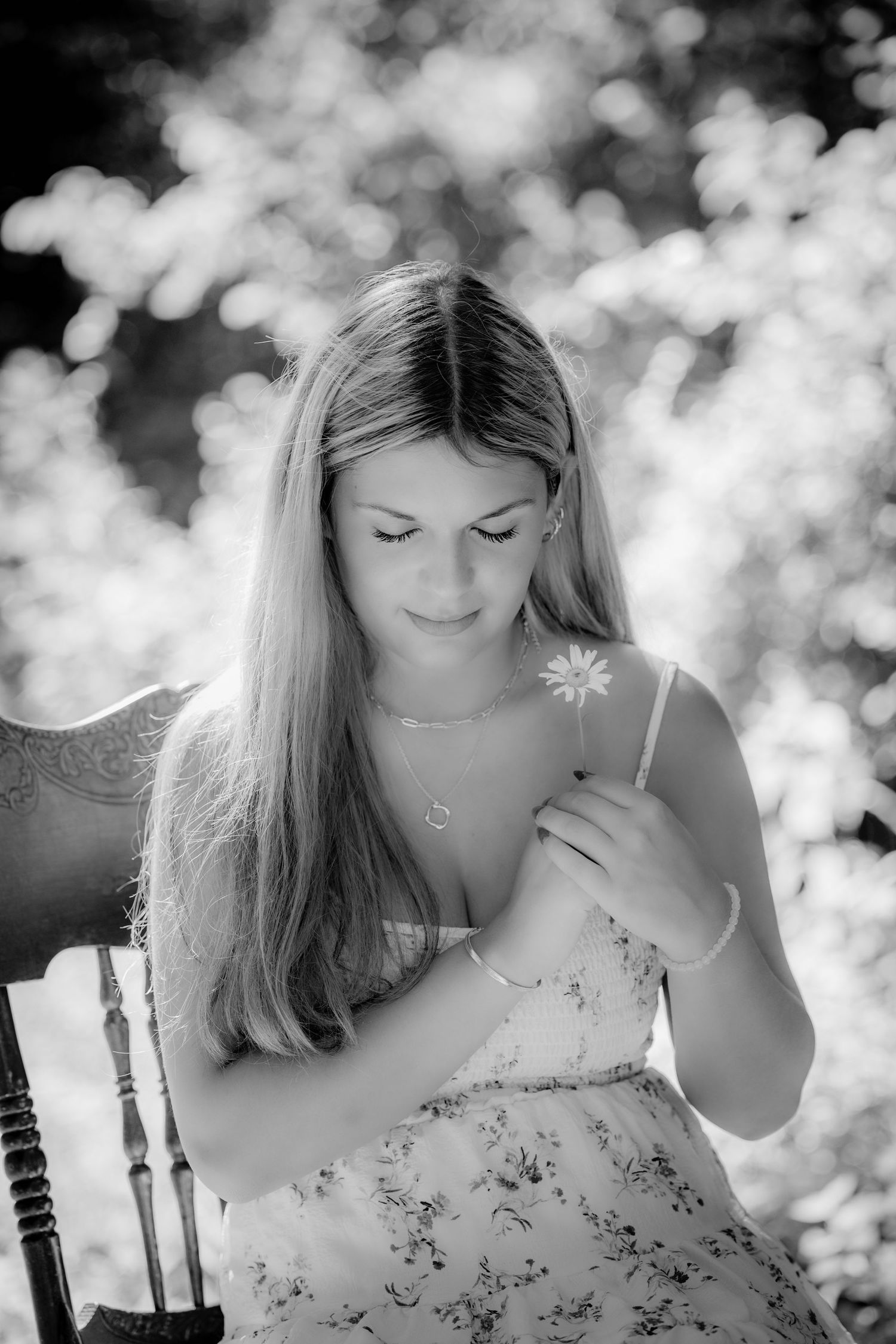 Senior - Black and white portrait of young woman holding a daisy flower outdoors.