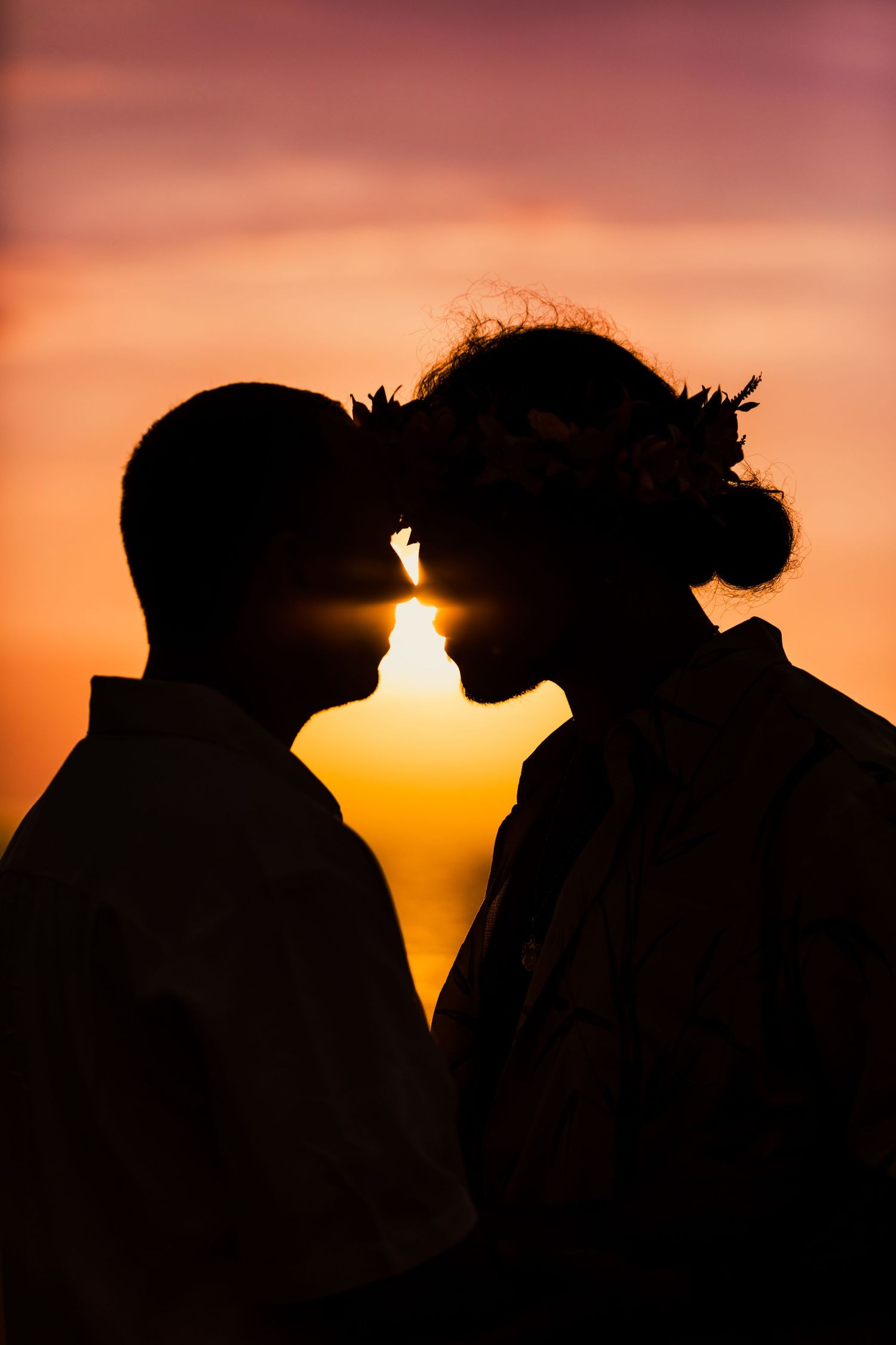 Silhouette of a romantic couple against a vibrant orange sunset sky.