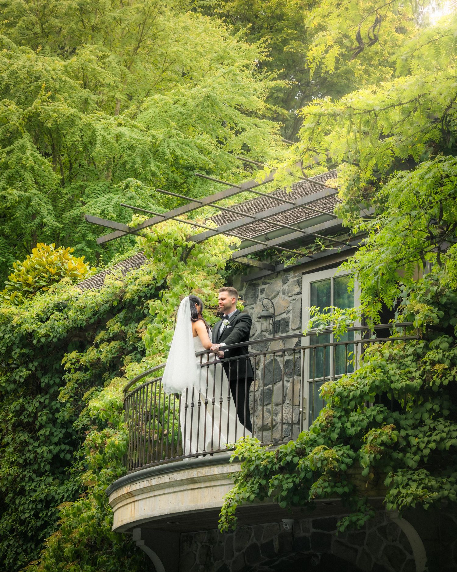 Bride and groom embracing on a balcony surrounded by lush greenery in la masion villa in vancouver