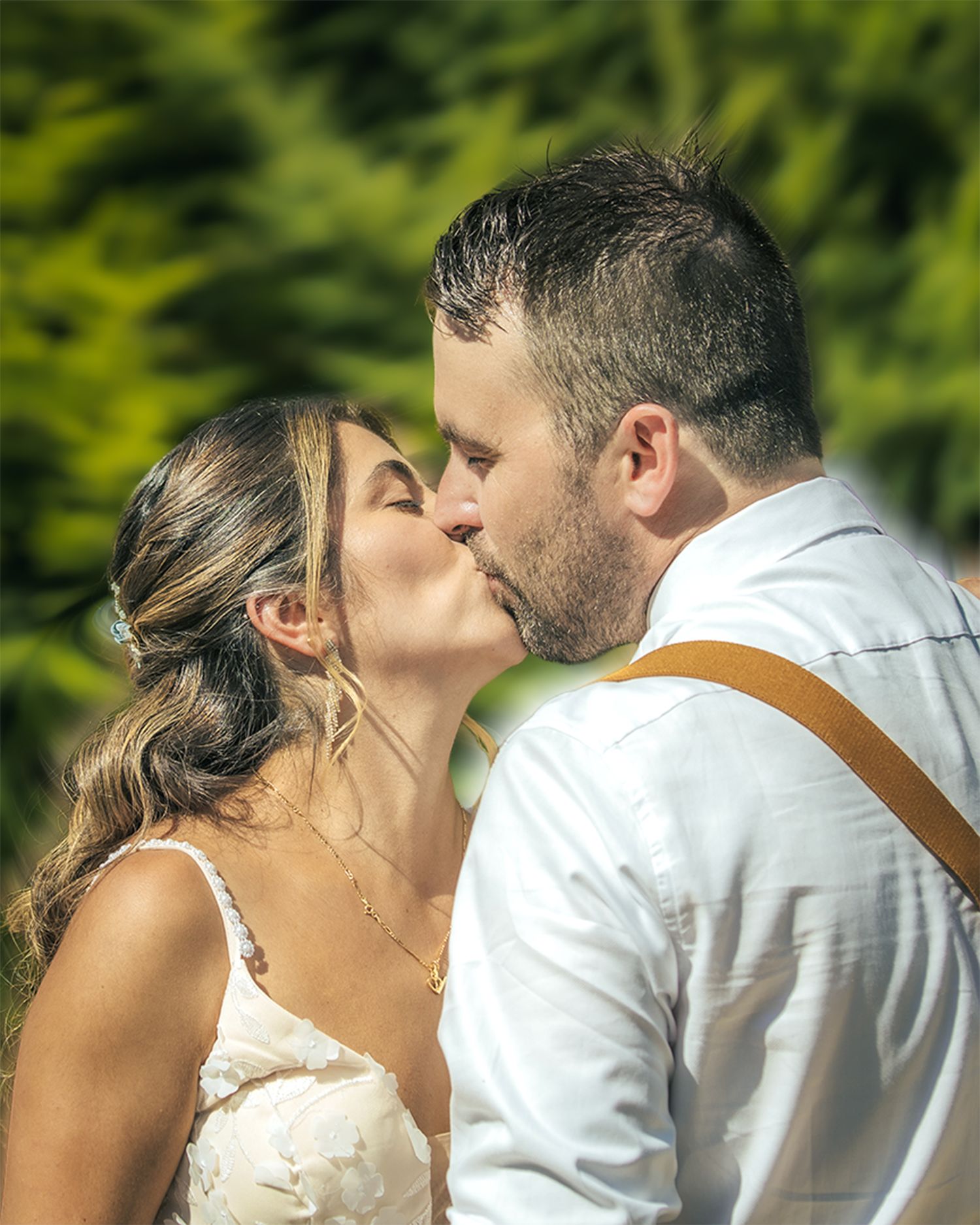 Bride and groom kissing surrounded by greenery at their wedding ceremony