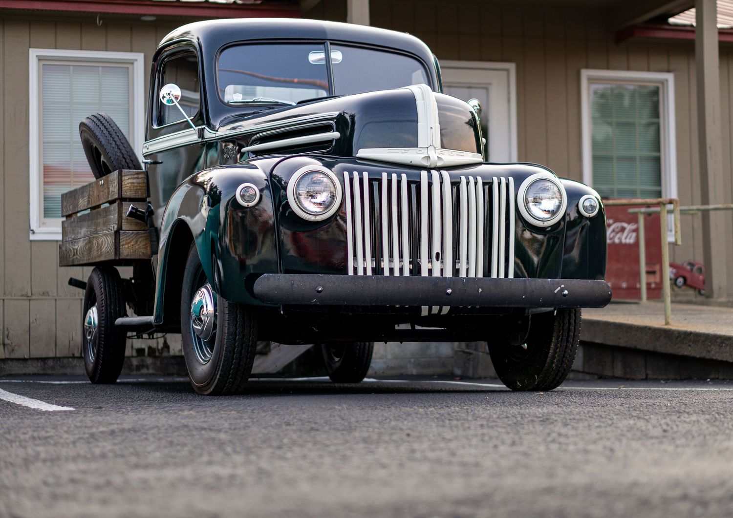 Vintage black Ford pickup truck parked outside a building, showcasing classic 1940s design with chrome grille.