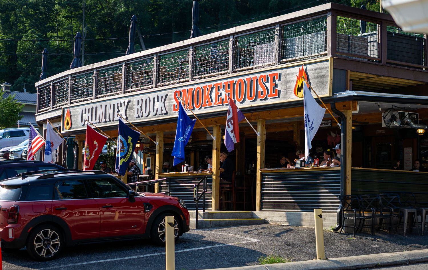 Chimney Rock Smokehouse restaurant exterior with flags and a red Mini Cooper parked outside in North Carolina.