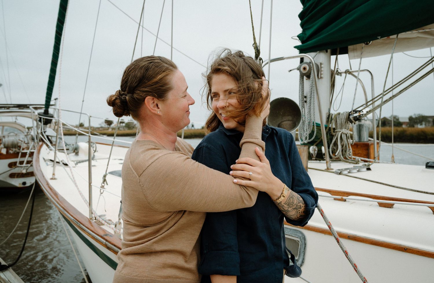 Couple embracing and smiling at each other on a sailboat at a marina.