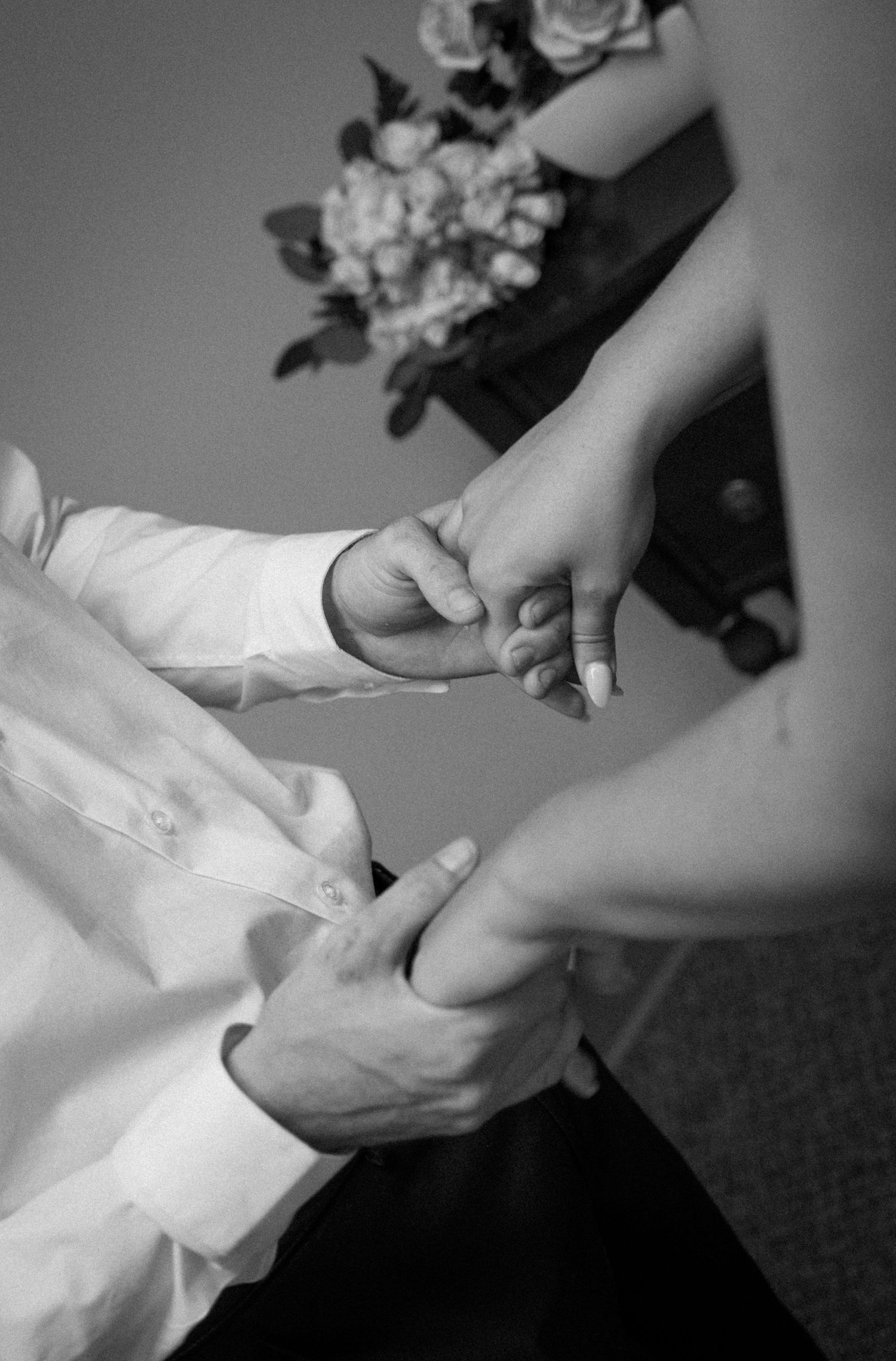Close-up black and white photo of groom placing wedding ring on bride's hand.