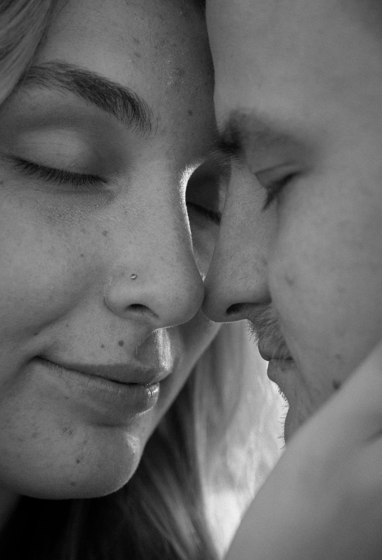 Intimate black and white close-up portrait of couple with foreheads nearly touching.