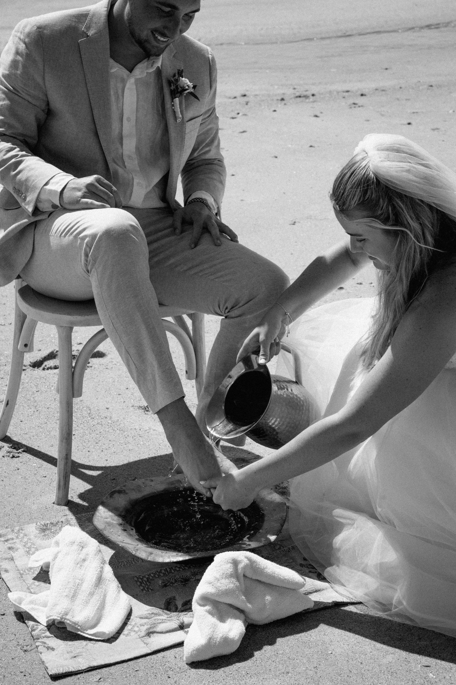Couple practicing feet washing at their beach wedding on Amelia Island, Florida