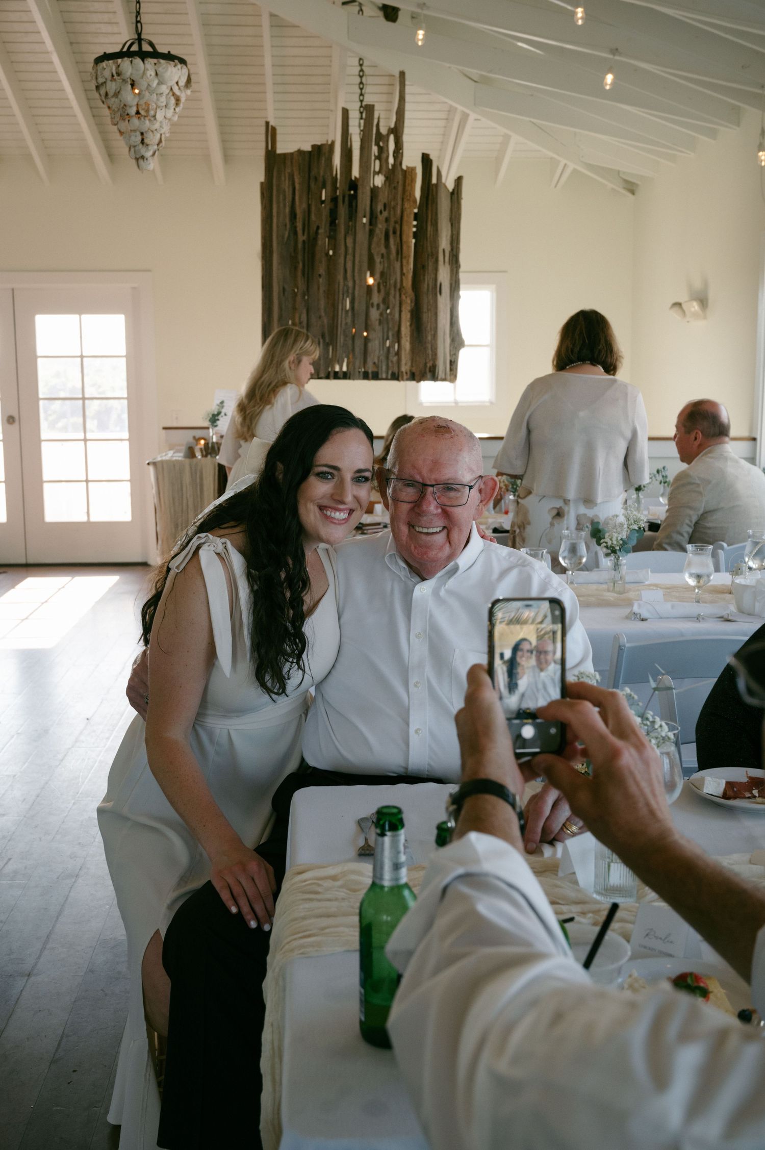 Bride posing with elderly guest for a photo at an elegant white wedding reception venue at Ocean Club of Amelia.