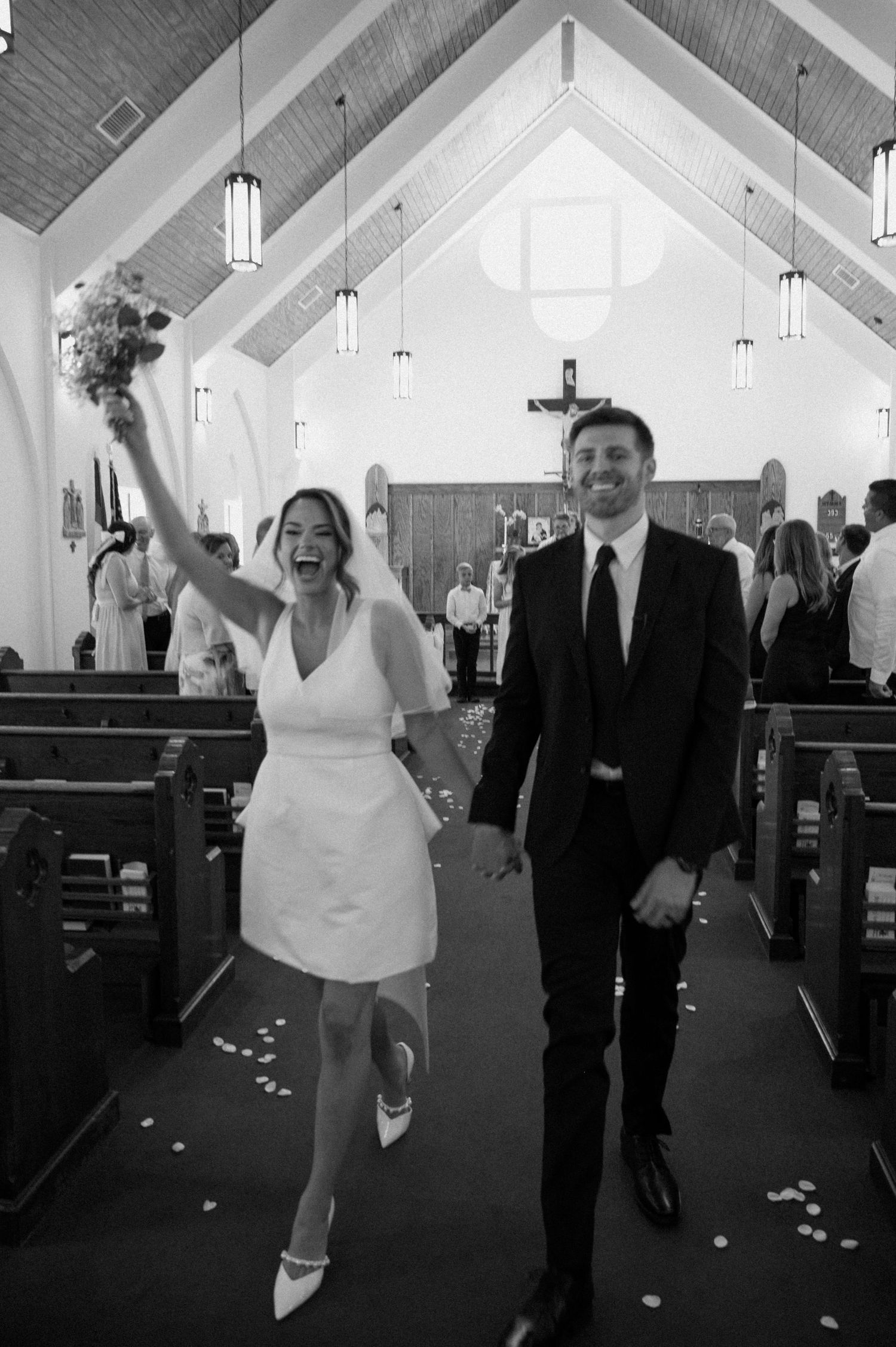 Joyful bride and groom walking down church aisle after wedding ceremony in black and white photo on Amelia Island, Florida.