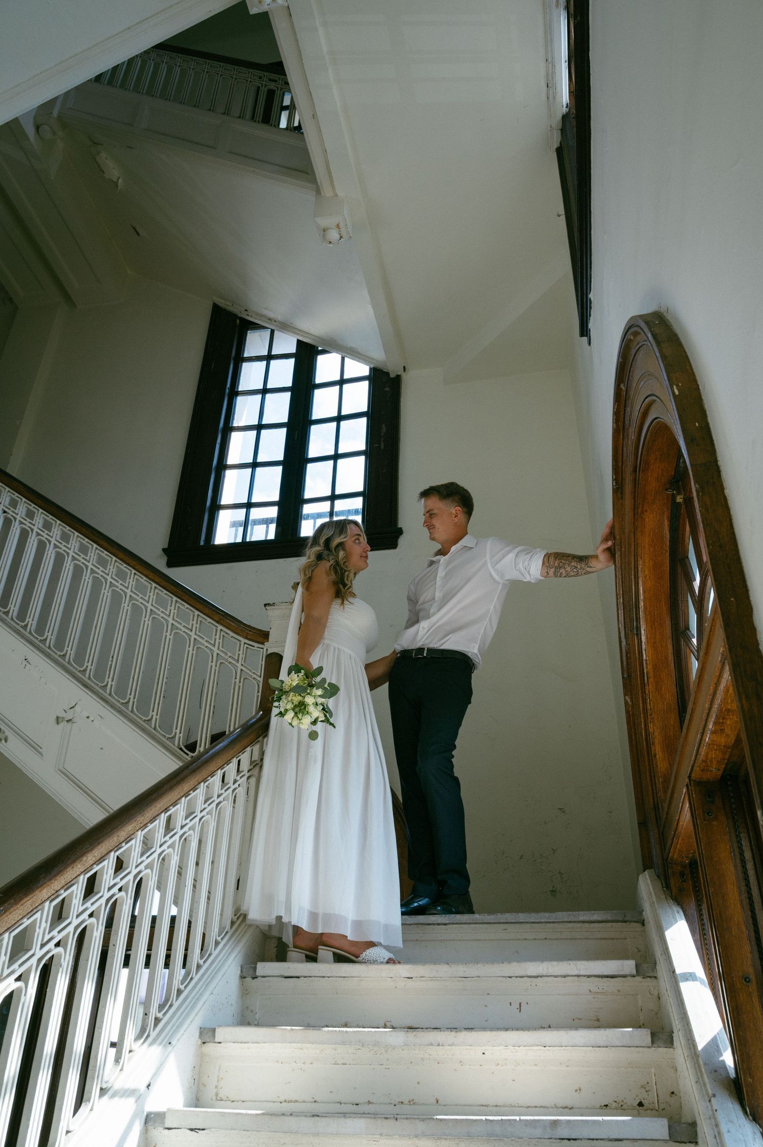 Newlywed couple standing on vintage staircase inside historic building after courthouse elopement on Amelia Island, Florida.