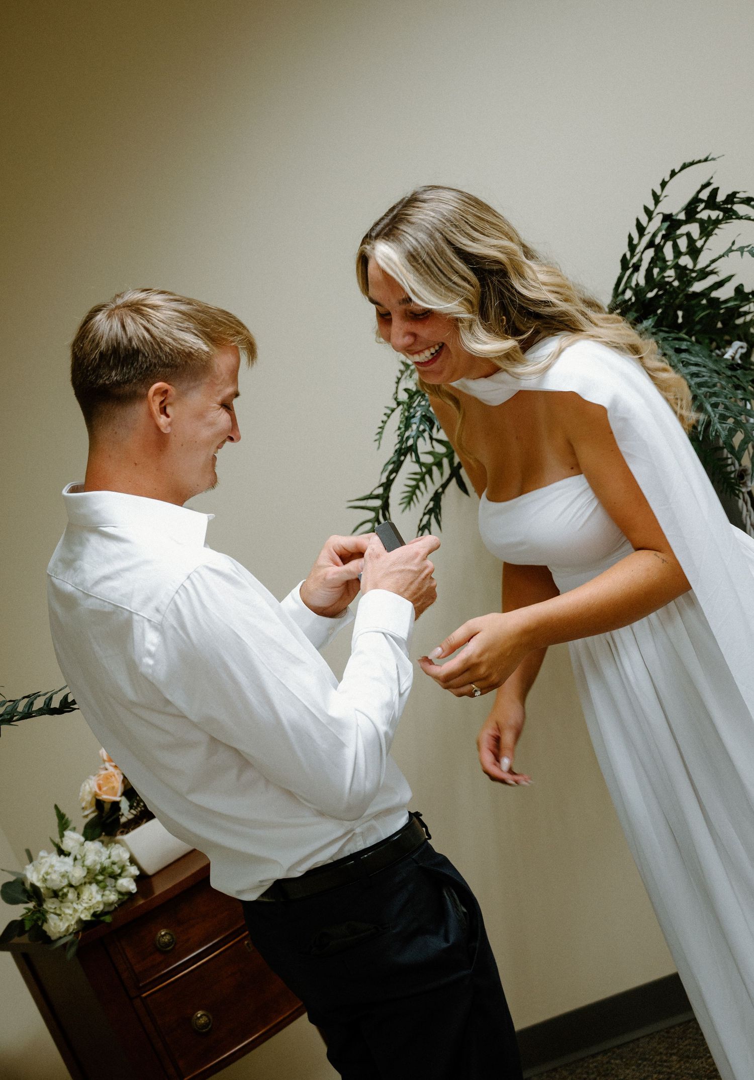 Groom places wedding ring on bride's finger during intimate courthouse elopement ceremony indoors.
