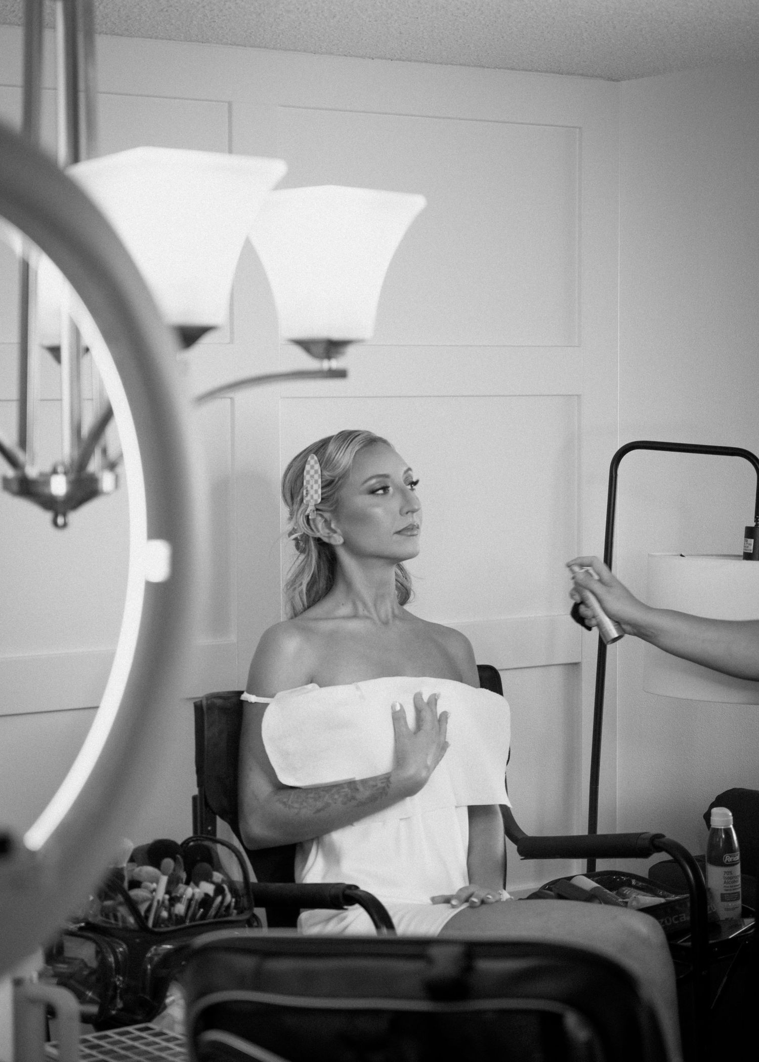 Bride getting hair and makeup done in black and white photo during wedding day preparations.
