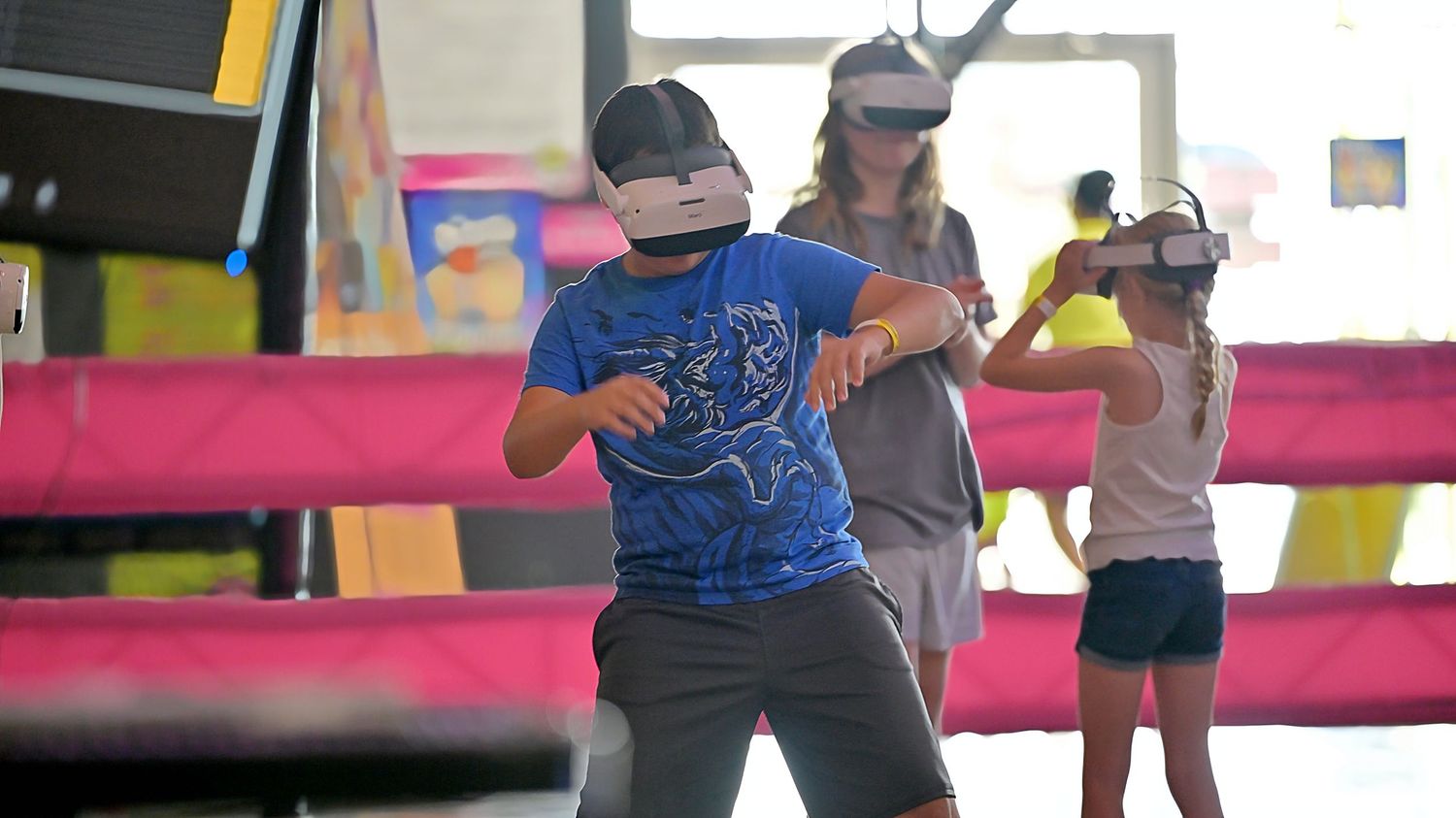 Children wearing VR headsets playing virtual reality games at an indoor entertainment center.