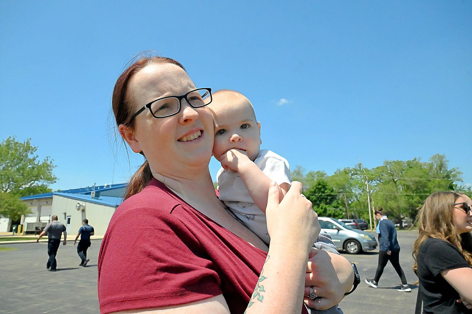 Smiling mother holding her happy baby outdoors on a bright sunny day.