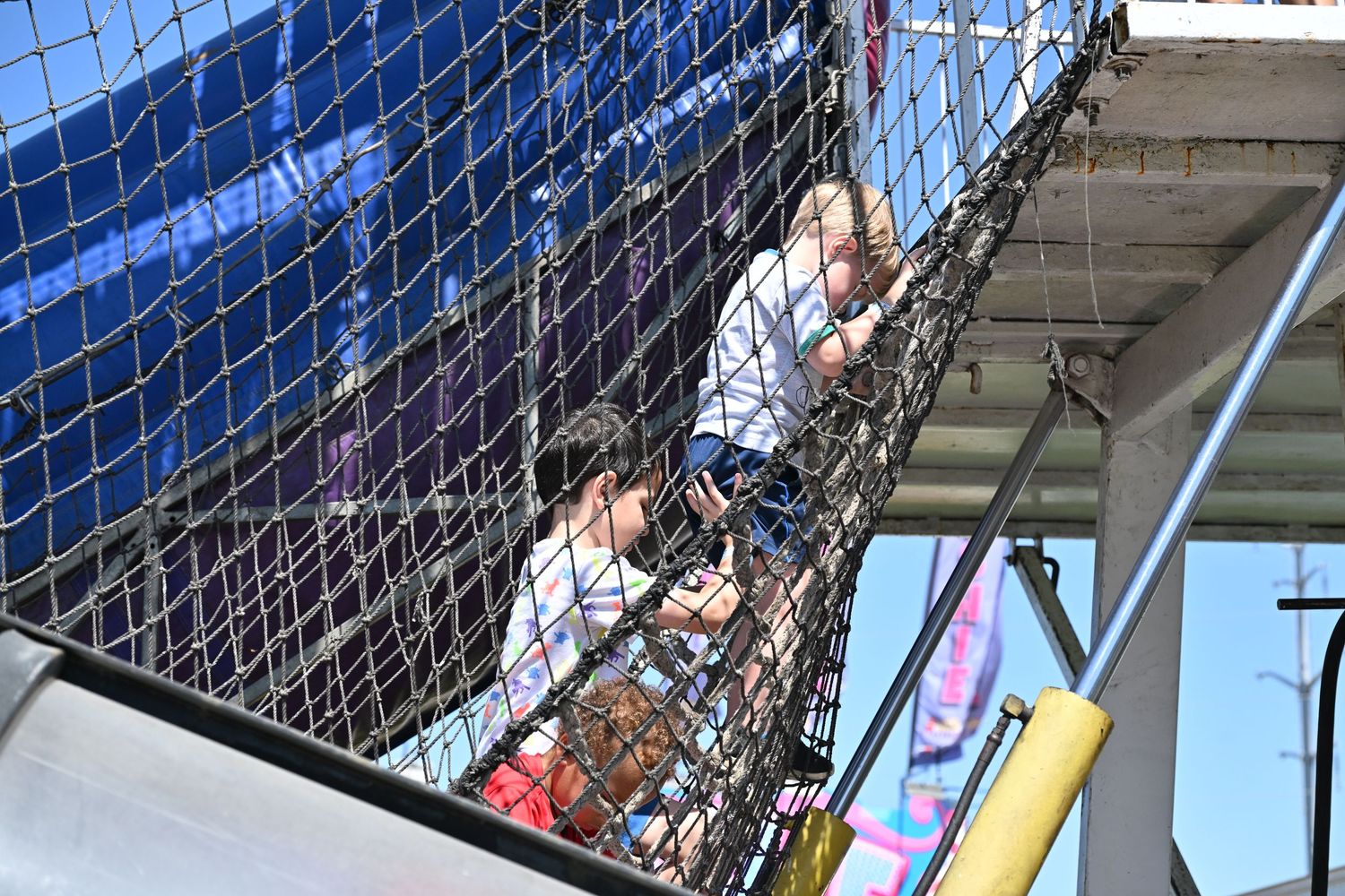 Two people climbing through a net obstacle course at an outdoor amusement attraction.