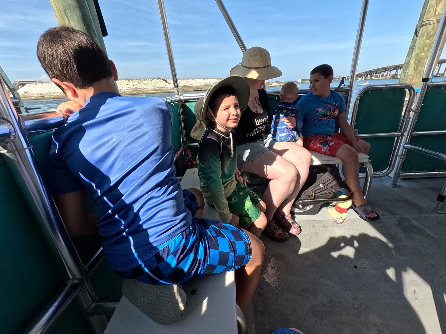 Family group sitting together on a boat deck during a sunny coastal excursion.