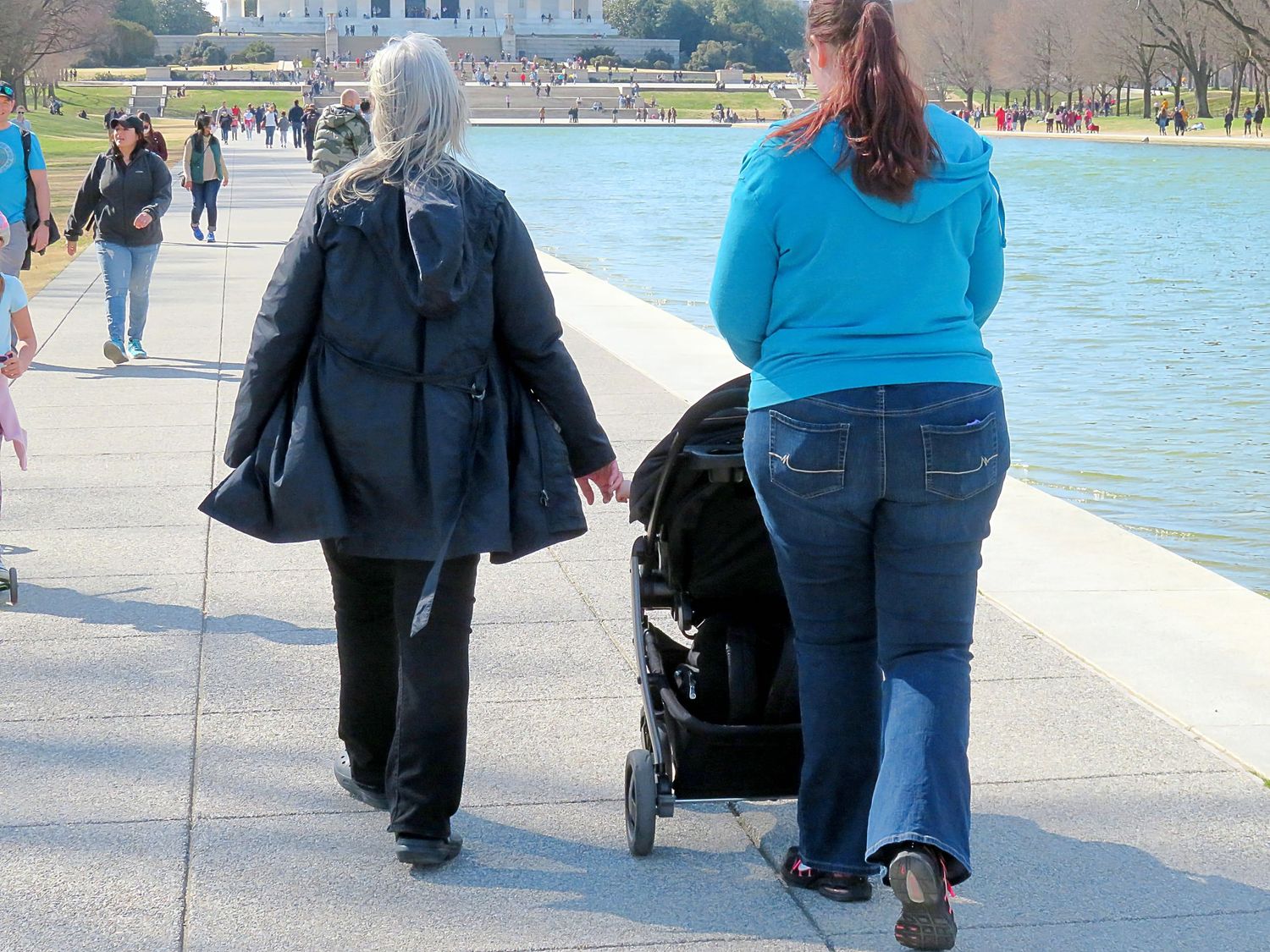 Two women walking with stroller along reflecting pool at National Mall Washington DC.
