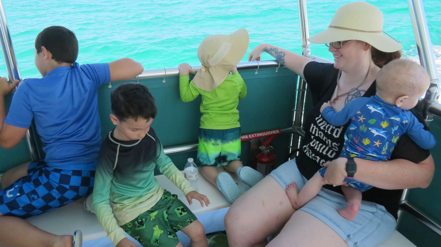 Family with young children enjoying a sunny boat ride on clear turquoise waters.