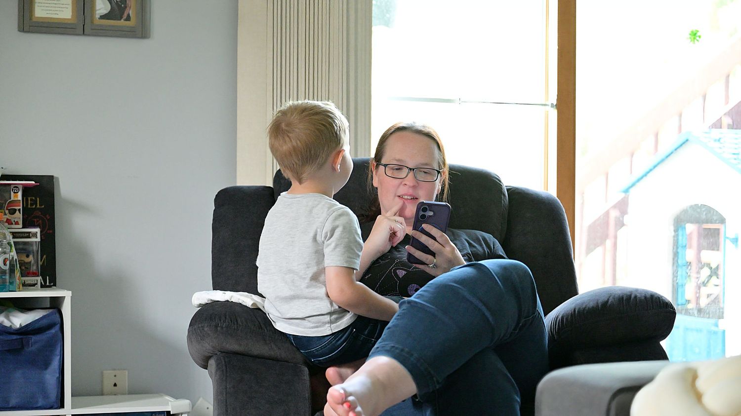 Adult and toddler sharing tablet on armchair indoors.