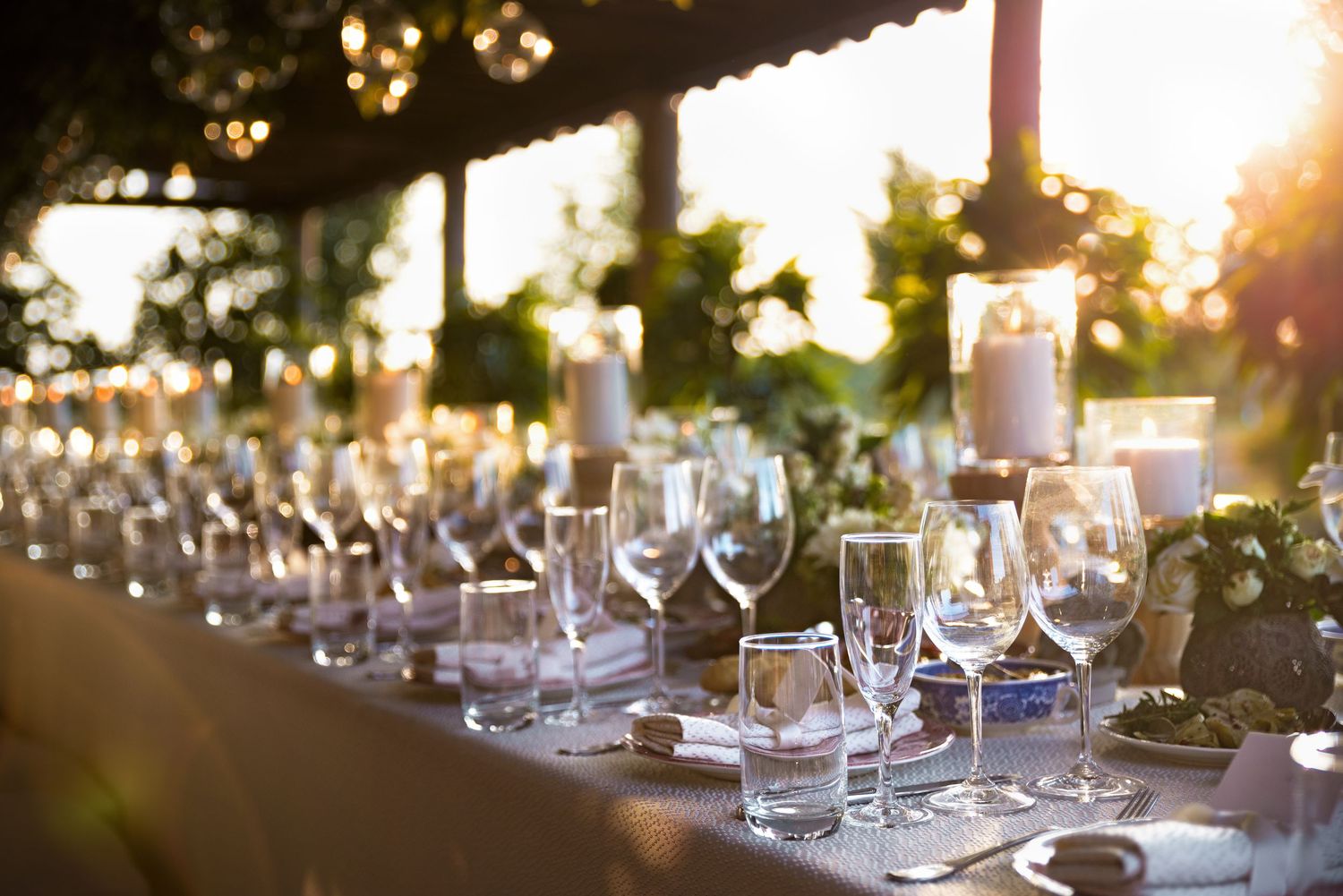 Elegant outdoor wedding reception table set with candles, wine glasses, and floral centerpieces.