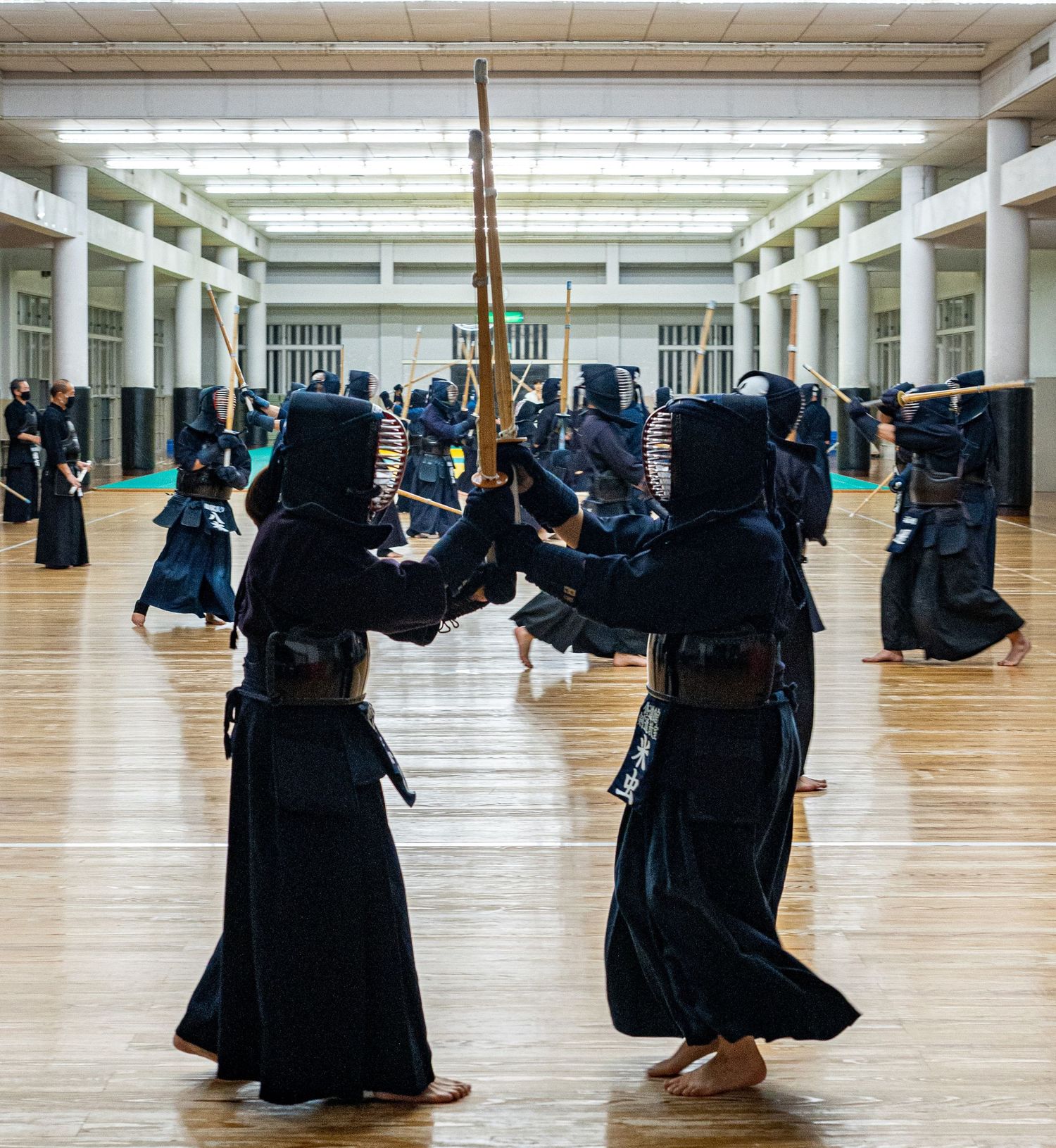 Kendo practitioners in full protective armor practice sword fighting techniques in a traditional Japanese dojo.