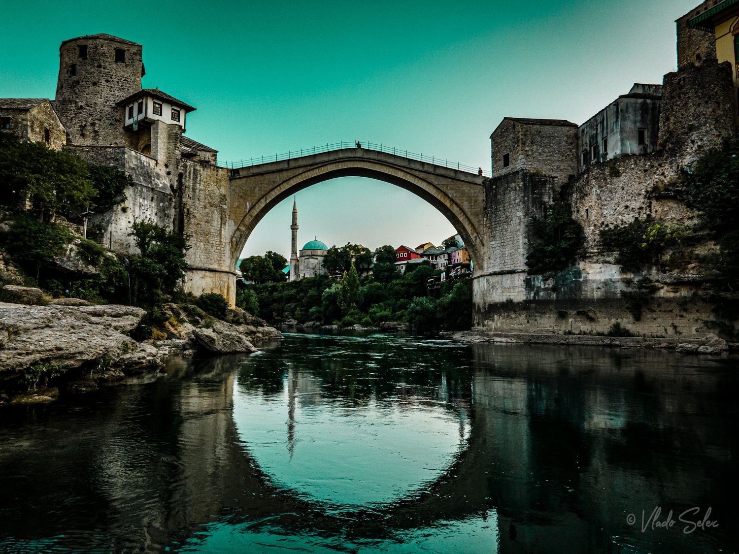 The iconic Stari Most stone arch bridge reflects in the turquoise Neretva River in Mostar, Bosnia.