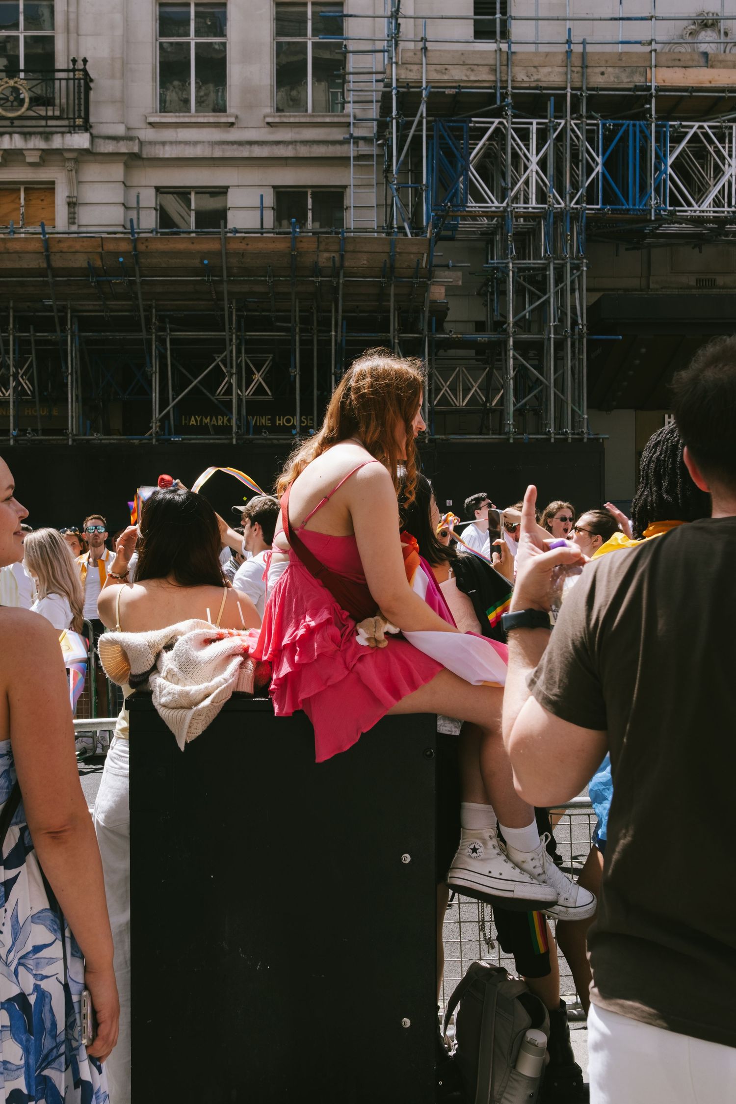 A woman sitting on top of an electrical box in central London watching the pride parade