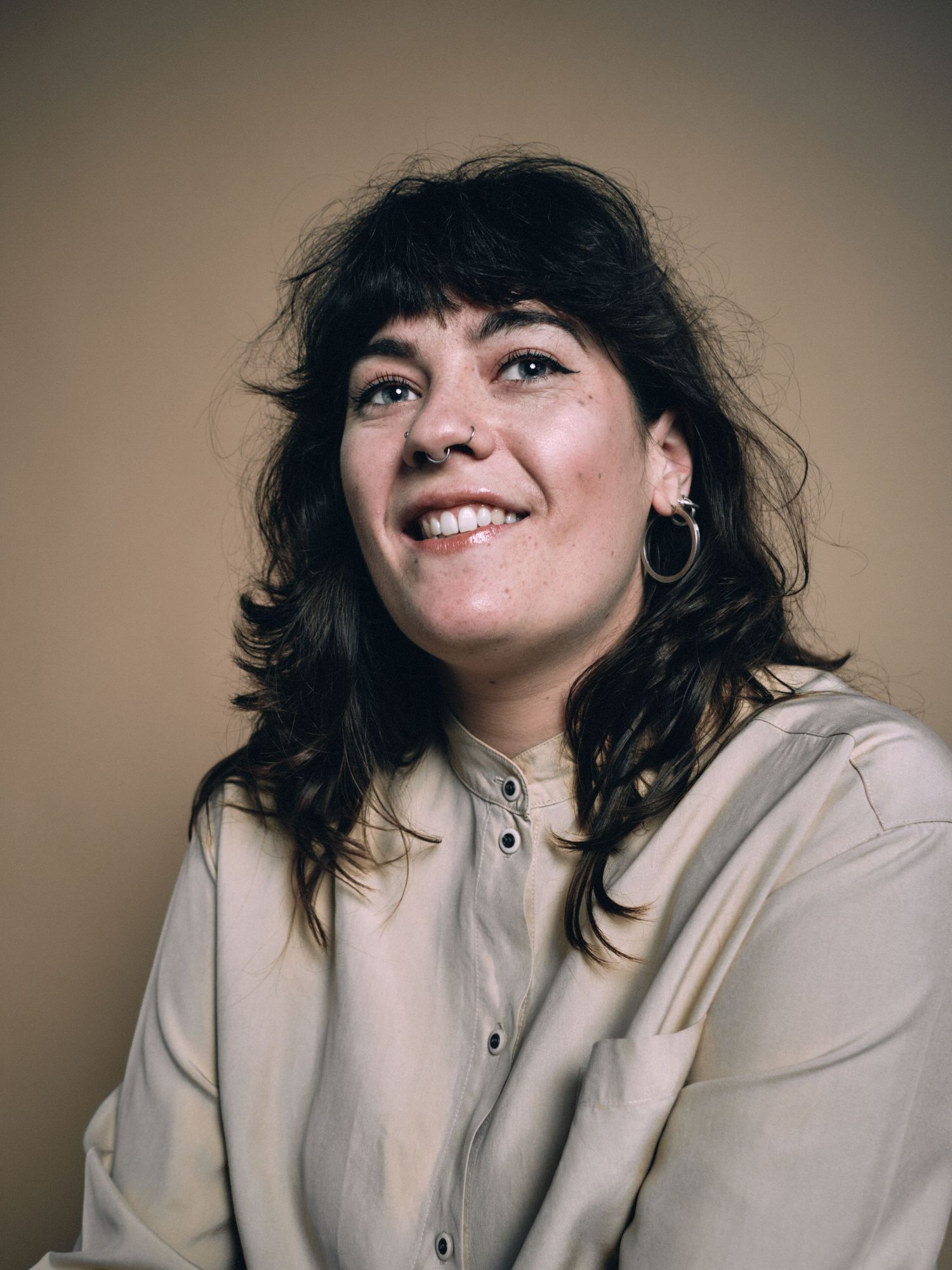 A head shot portrait of a woman in a cream coloured shirt, with brown hair