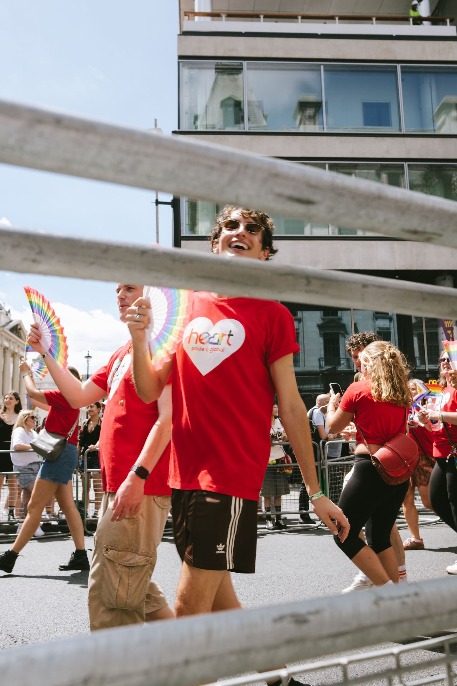 A man smiling whilst marching in the pride parade in London with the sun out