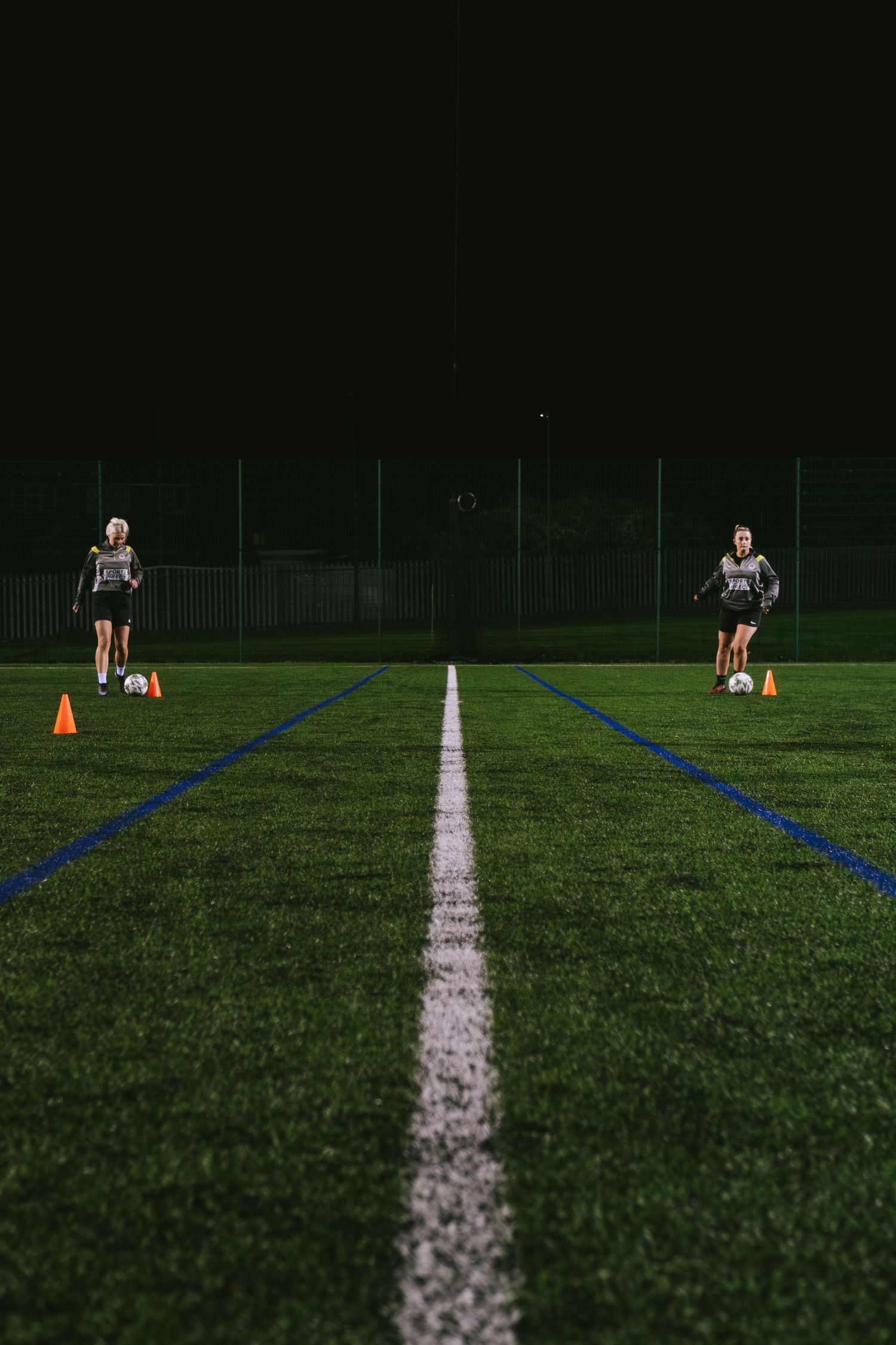 2 women playing football on astro turf