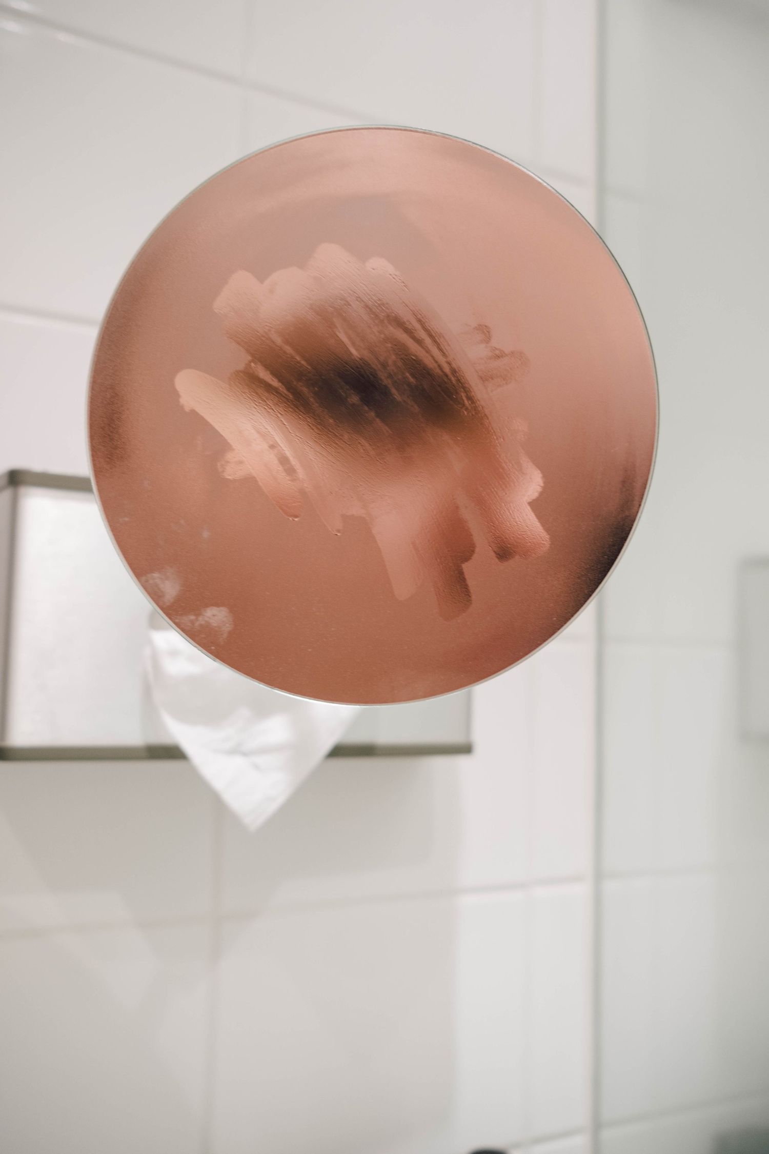 An abstract self portrait showing an eye and part of a nose in a circular bathroom vanity mirror