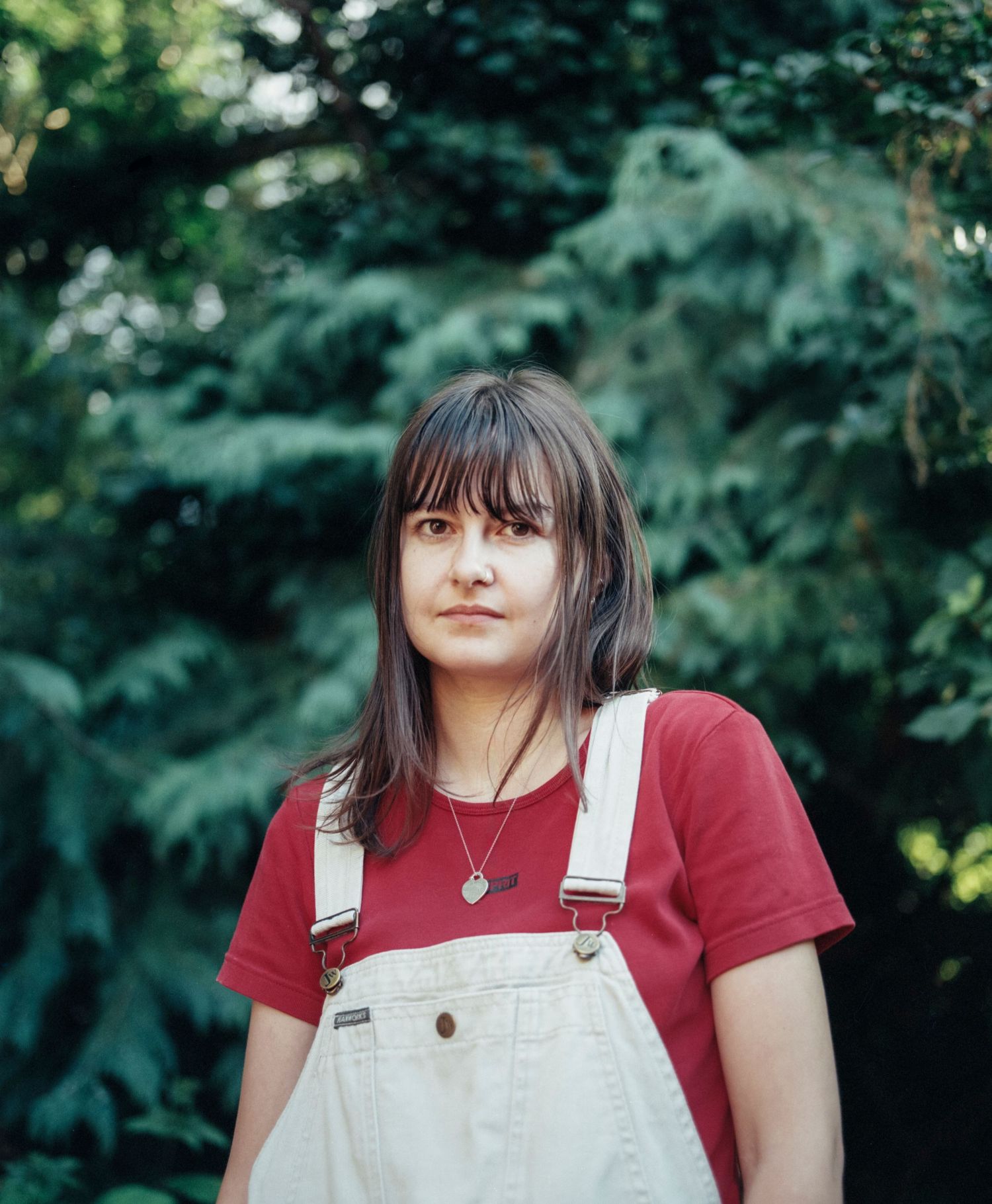 A head shot portrait of a woman outdoors in front of green trees