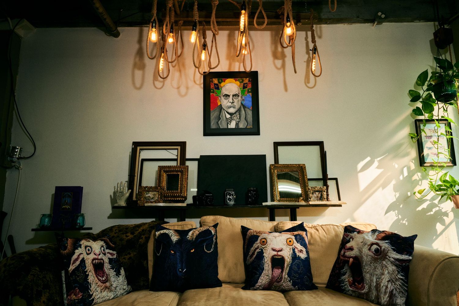 Cozy lounge with Edison bulb chandelier, framed portrait art, and decorative animal-print throw pillows on a beige sofa.