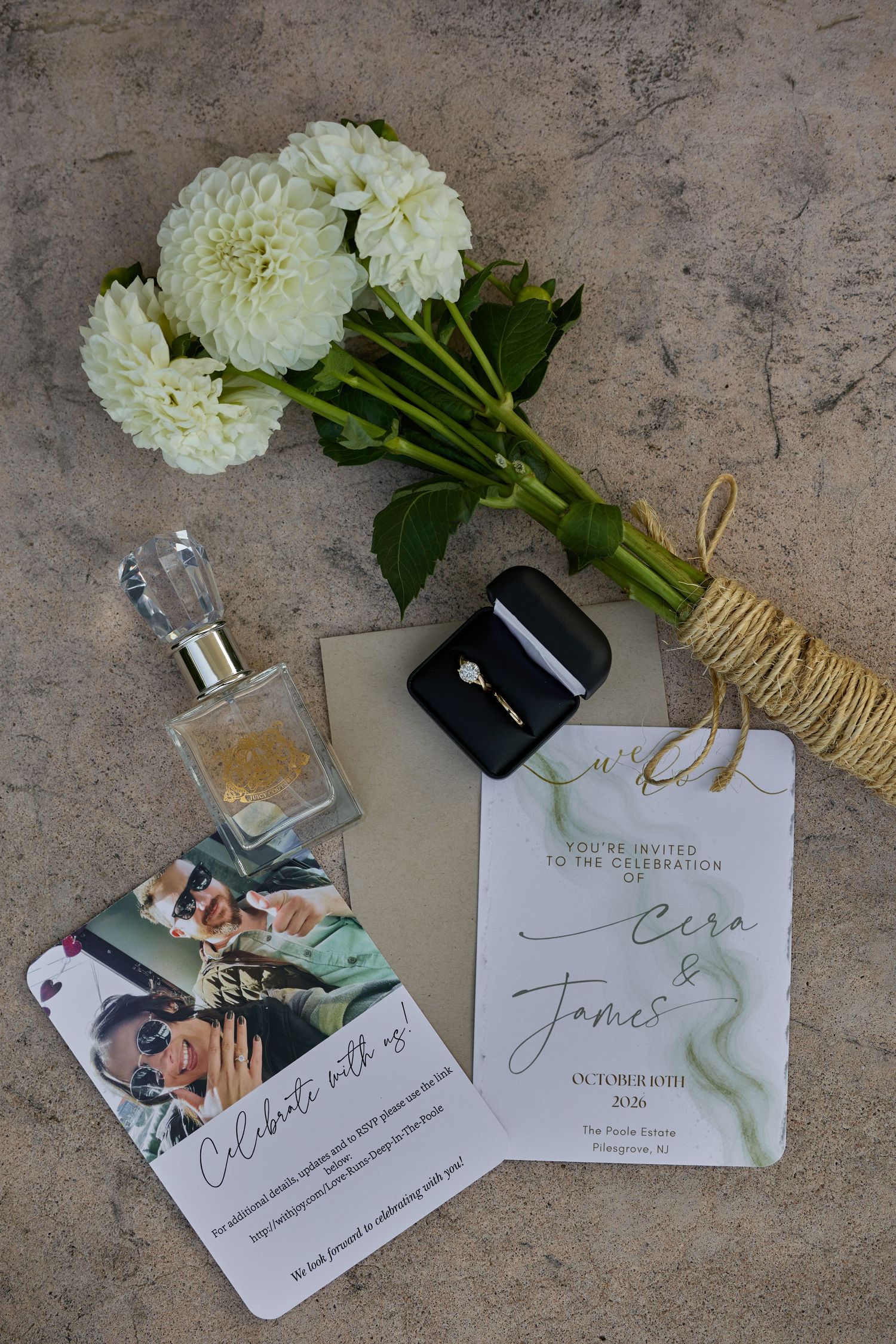 Wedding flat lay with white dahlias, perfume bottle, engagement ring box, and an invitation for Cera and James.