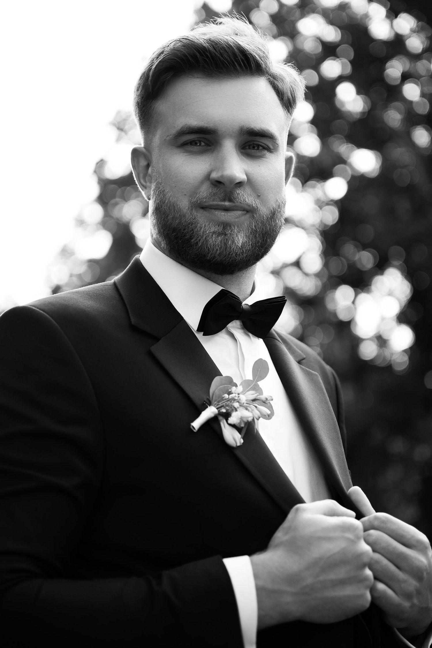 Black and white portrait series of groom in tuxedo adjusting boutonniere.