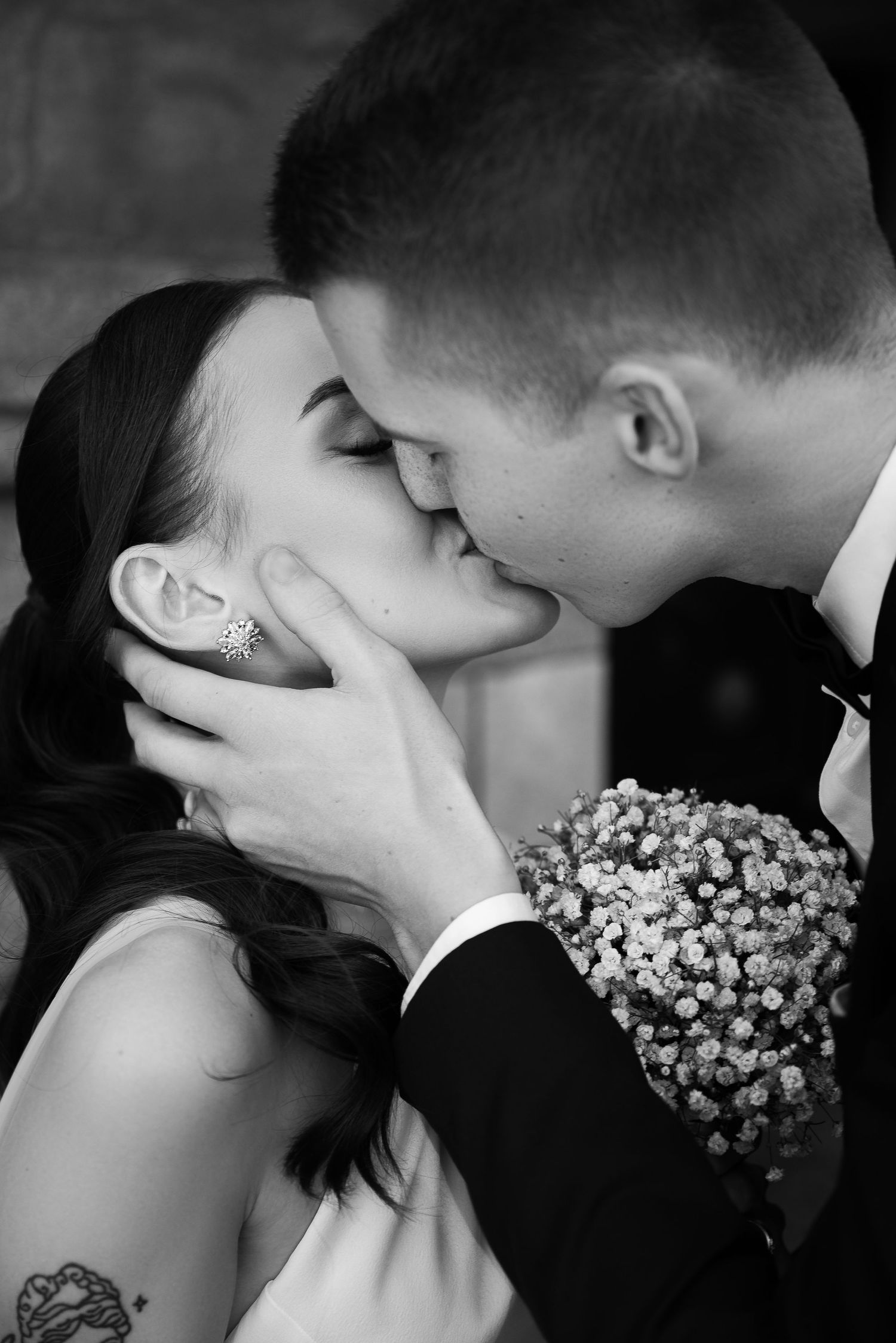 Intimate black and white wedding portraits showing couple kissing with floral details.