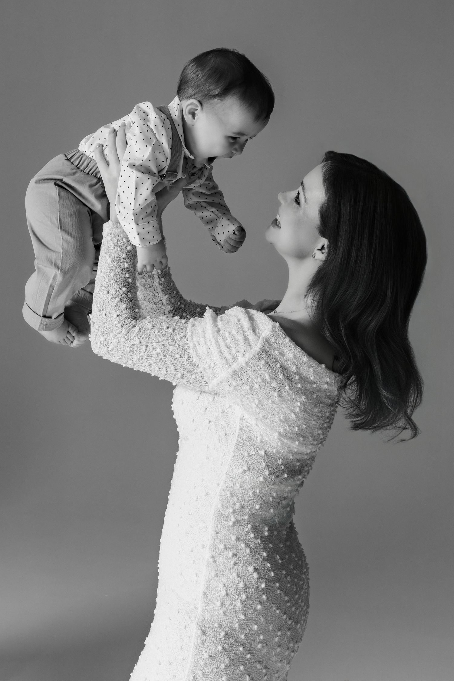 A series of black and white photos showing tender moments between parent and child in matching white lace outfits.