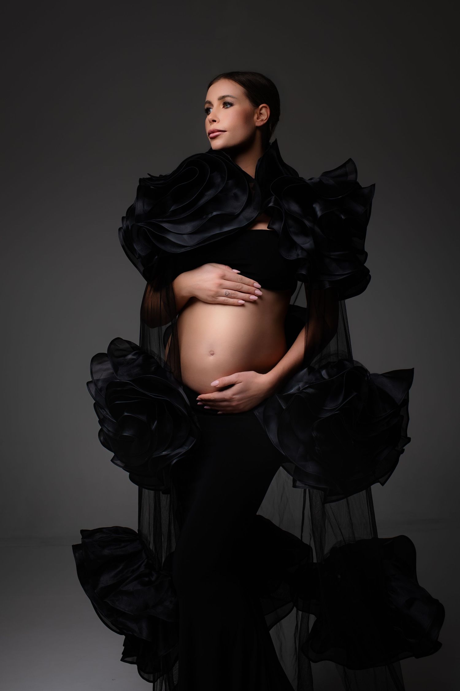 Artistic maternity portraits with black flowing dress in studio setting.