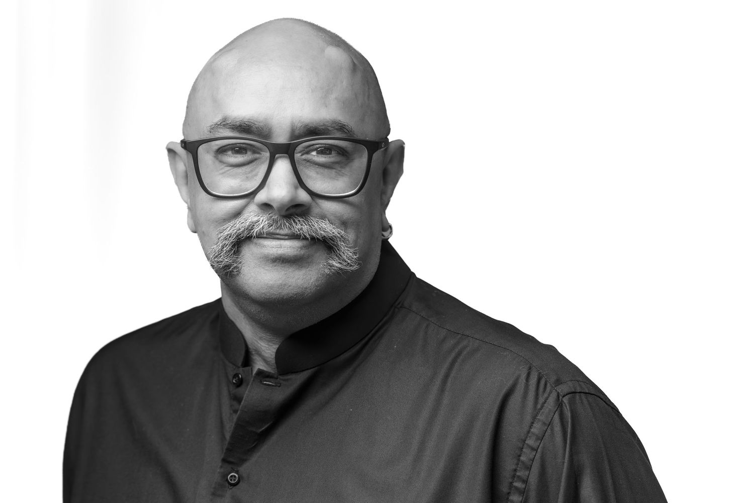 Bald man with glasses and mustache in black shirt, professional black and white portrait photo.