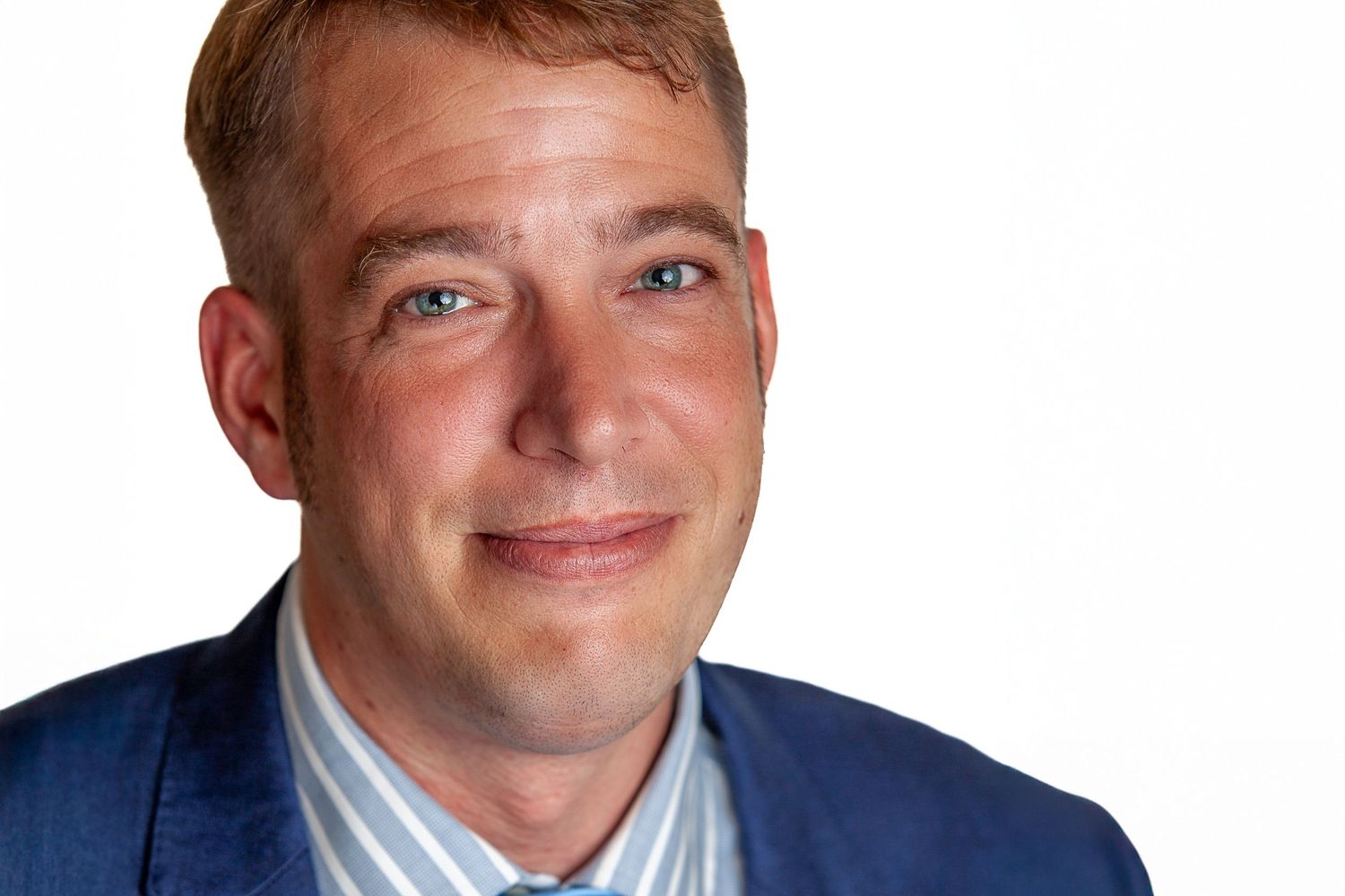 Business professional smiling at camera in formal attire against white backdrop.