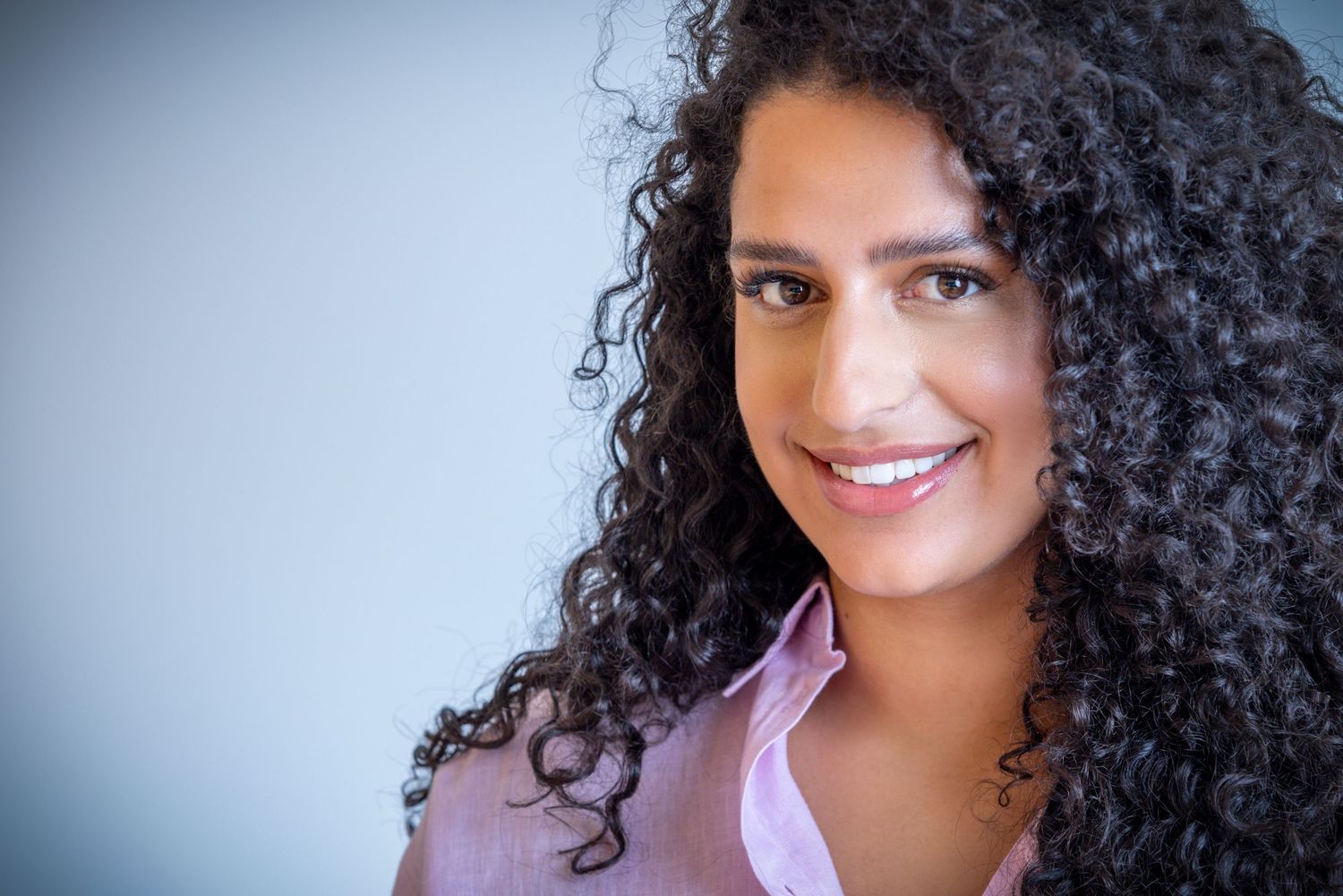 A series of seven selfie photos showing someone with curly dark hair wearing a pink top against light backgrounds.