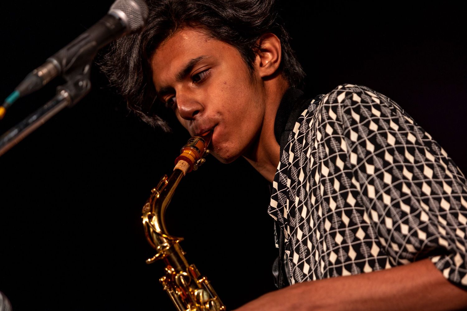 Close-up shot of saxophone player performing with dramatic side lighting.