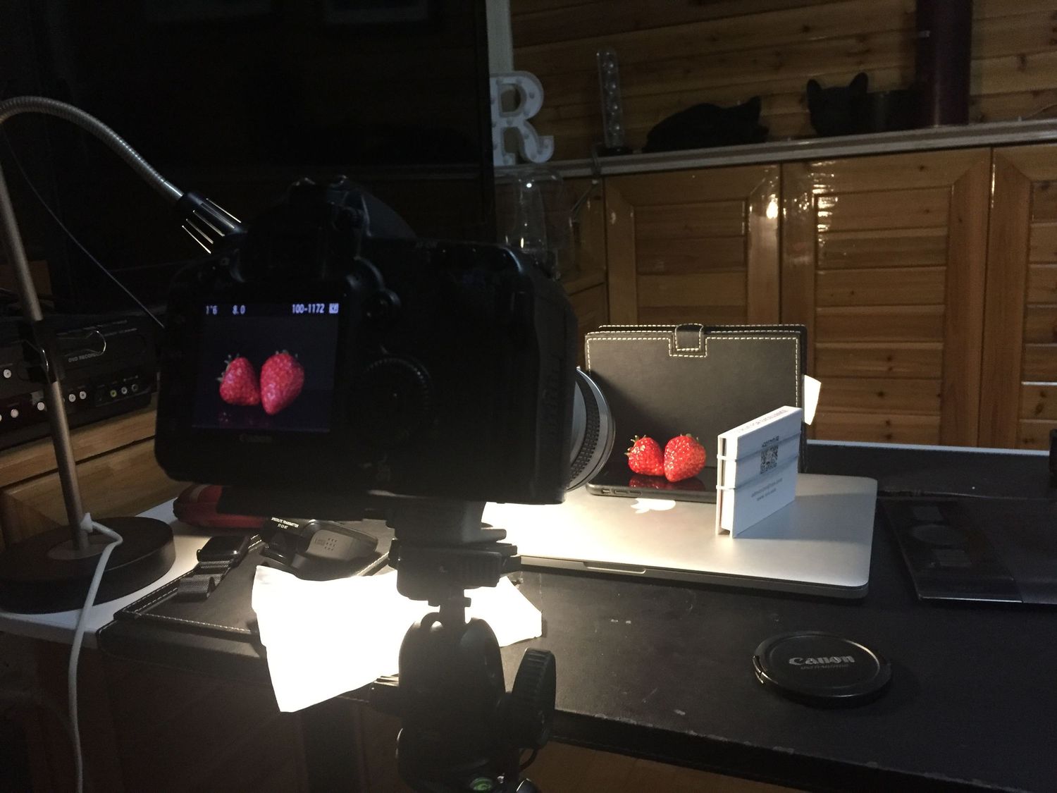 Camera setup showing red lights and equipment on dark desk for photography.