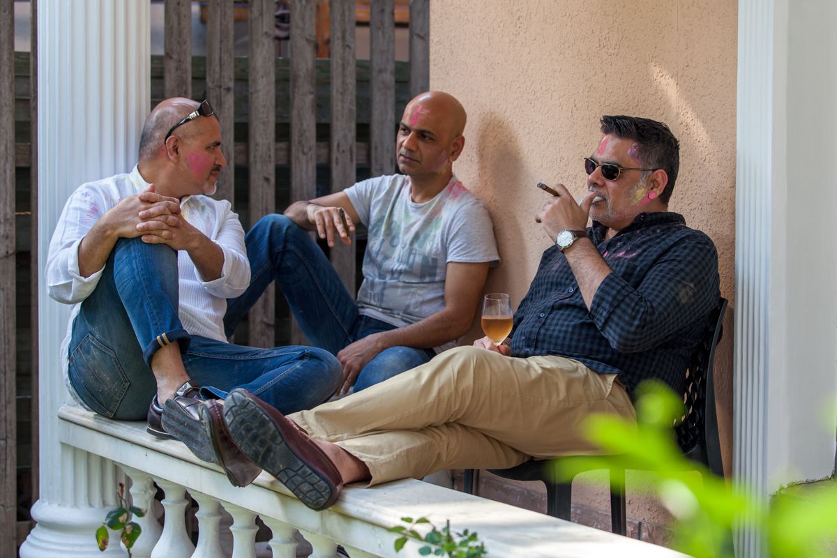 Three friends relaxing and chatting on a porch with casual summer vibes.